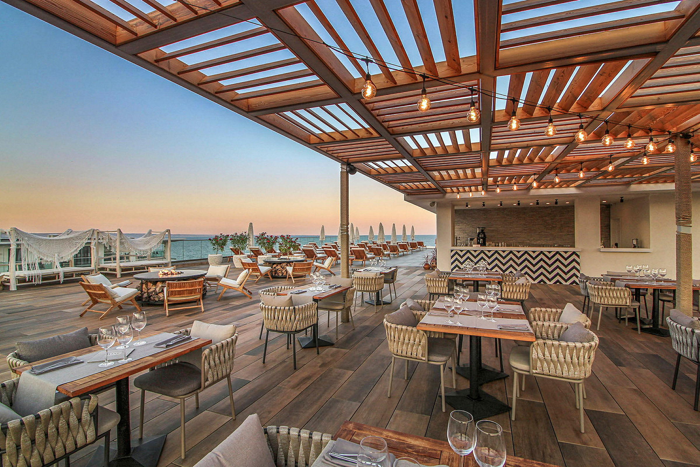 Restaurant med terrasse og havudsigt under træpergola. (AI-genereret tekst)