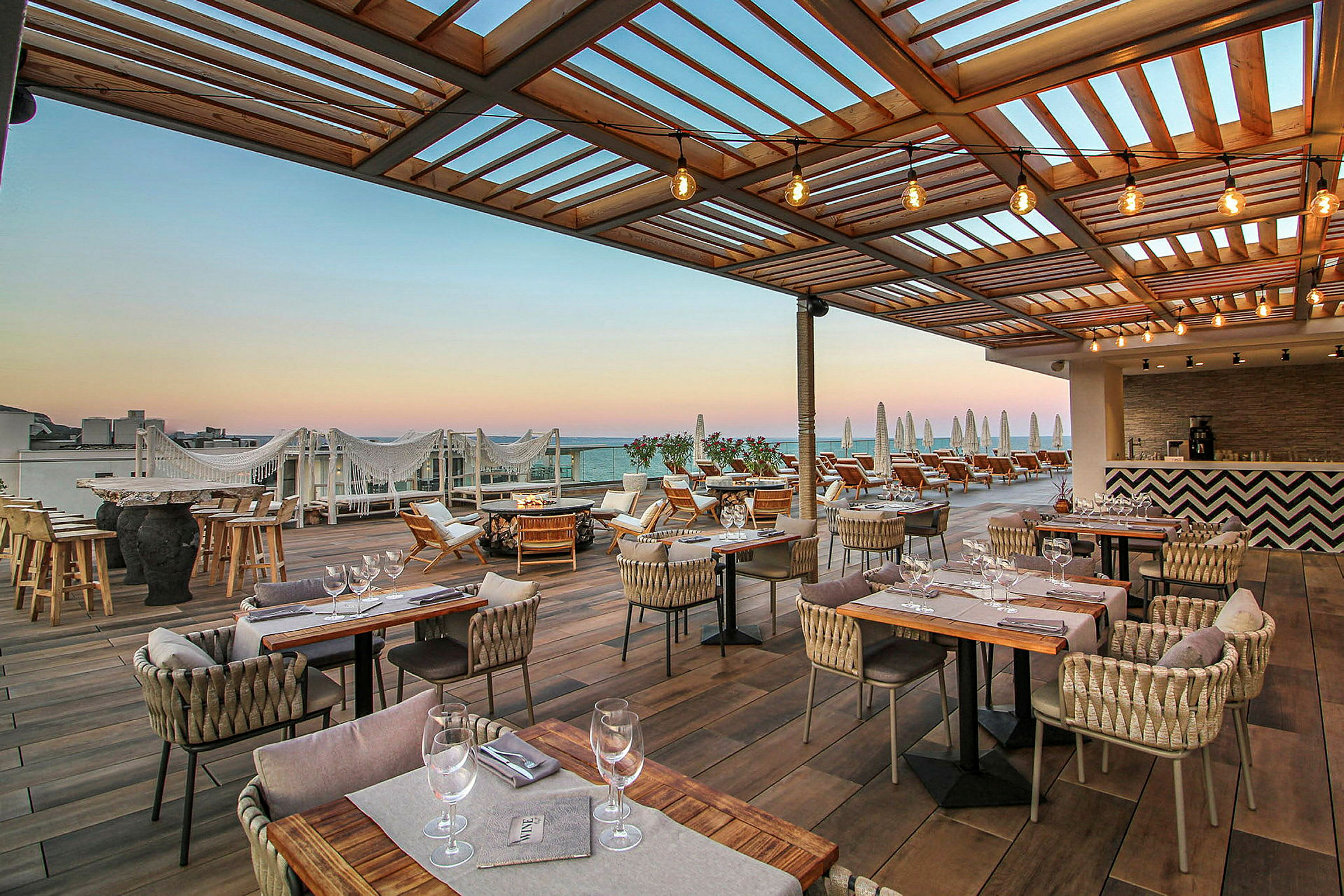 Terrasse med udendørsrestaurant og liggestole under træpergola. (AI-genereret tekst)