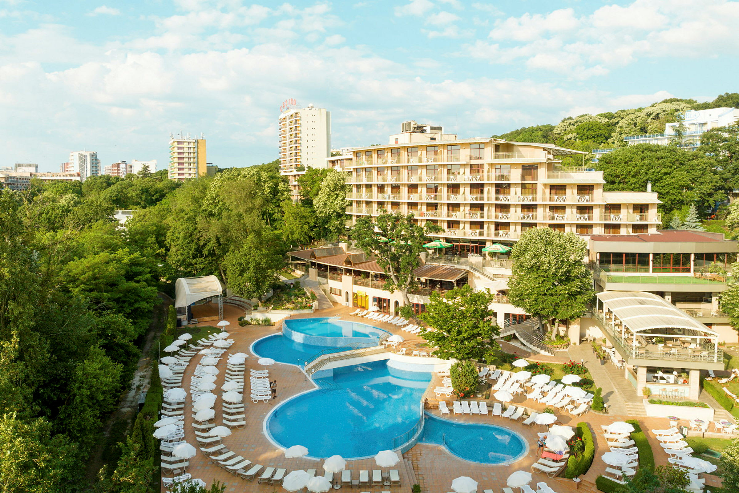 Et hotel med en pool og liggestole, omgivet af grønt. (AI-genereret tekst)