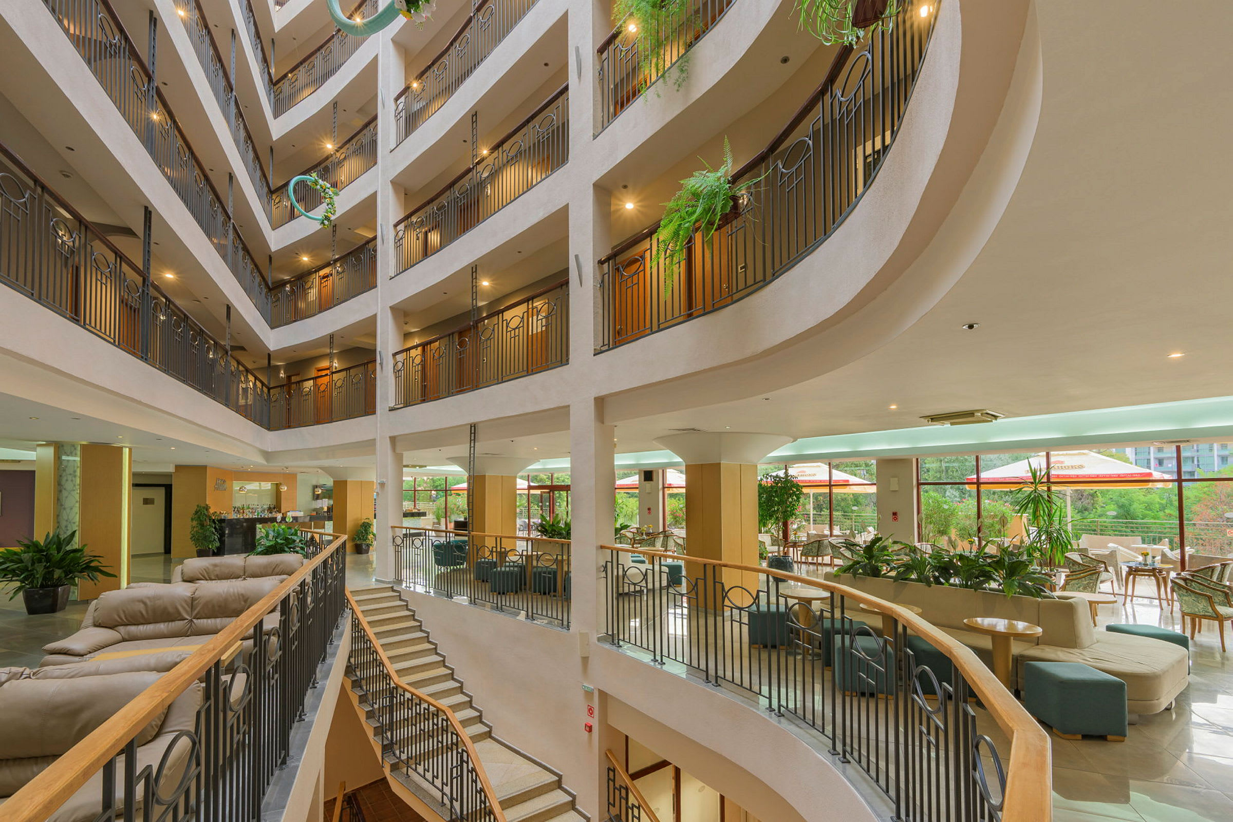 Interiør af et hotel med et flerfoldigt atrium, siddegrupper og planter. (AI-genereret tekst)