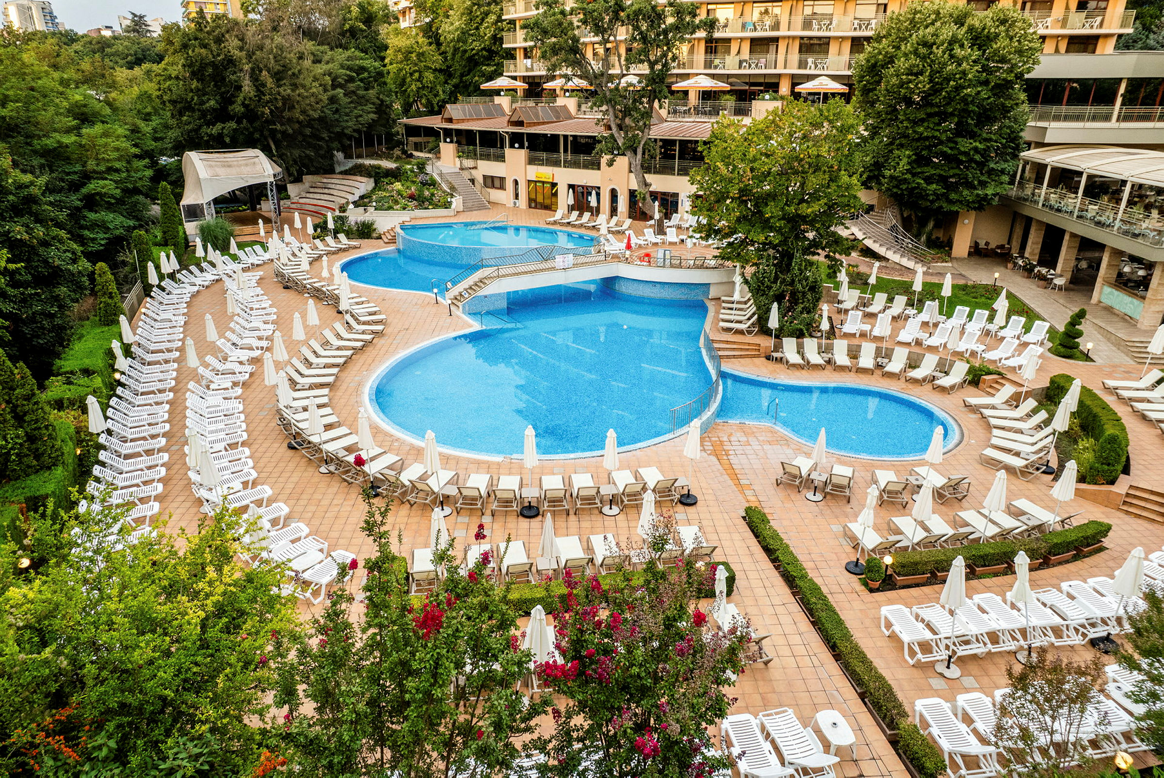 Billede af et hotelområde med flere swimmingpools og liggestole. (AI-genereret tekst)