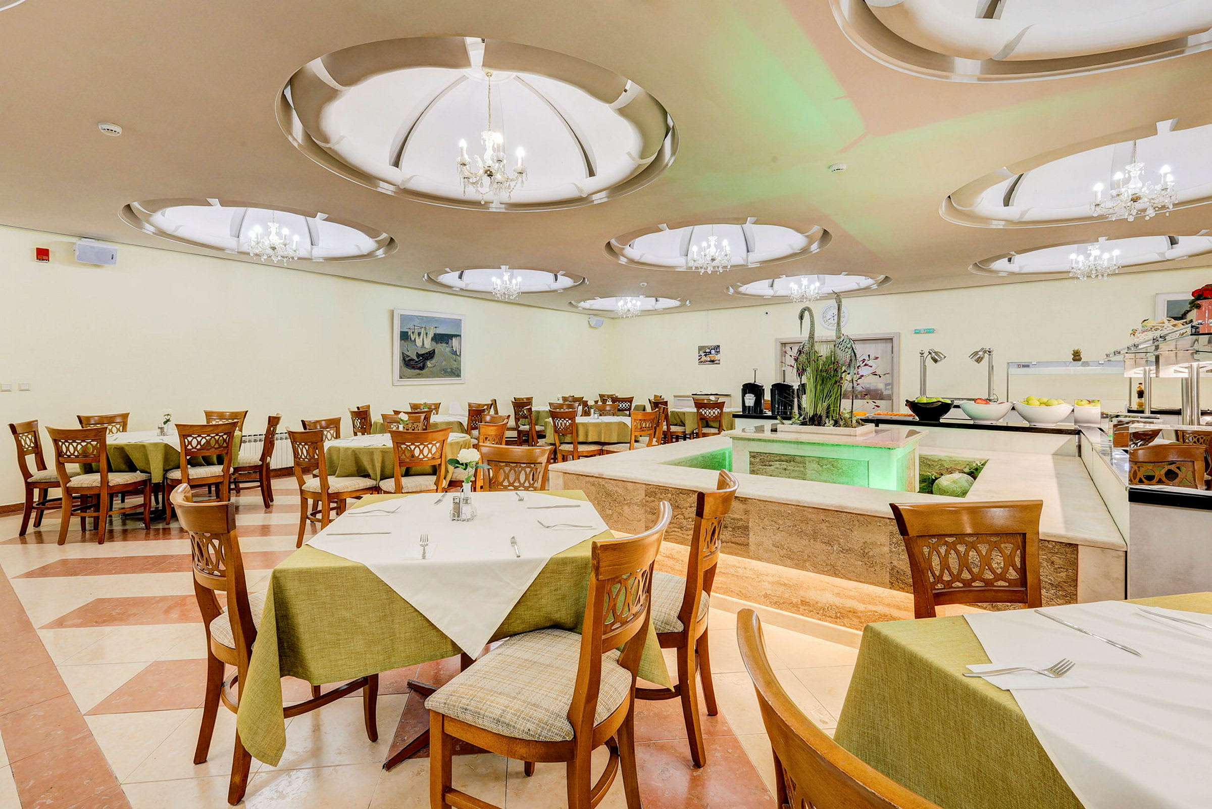 Billede af en restaurant med træstole og borde dækket med grønne duge. I baggrunden ses dekorationer og en buffet. (AI-genereret tekst)