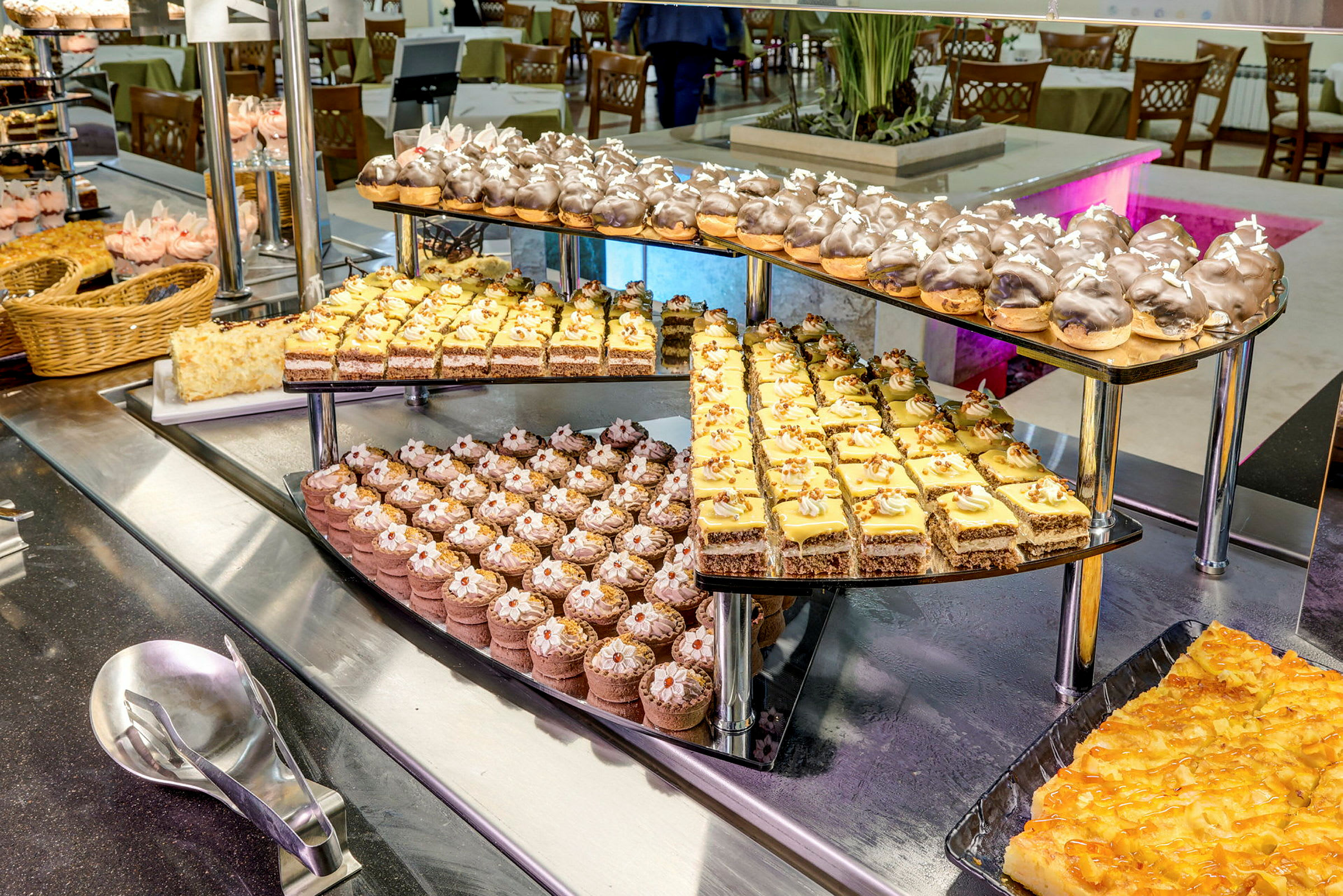 Et dessertbord med et udvalg af forskellige bagværk og kager på et serveringsstativ. (AI-genereret tekst)