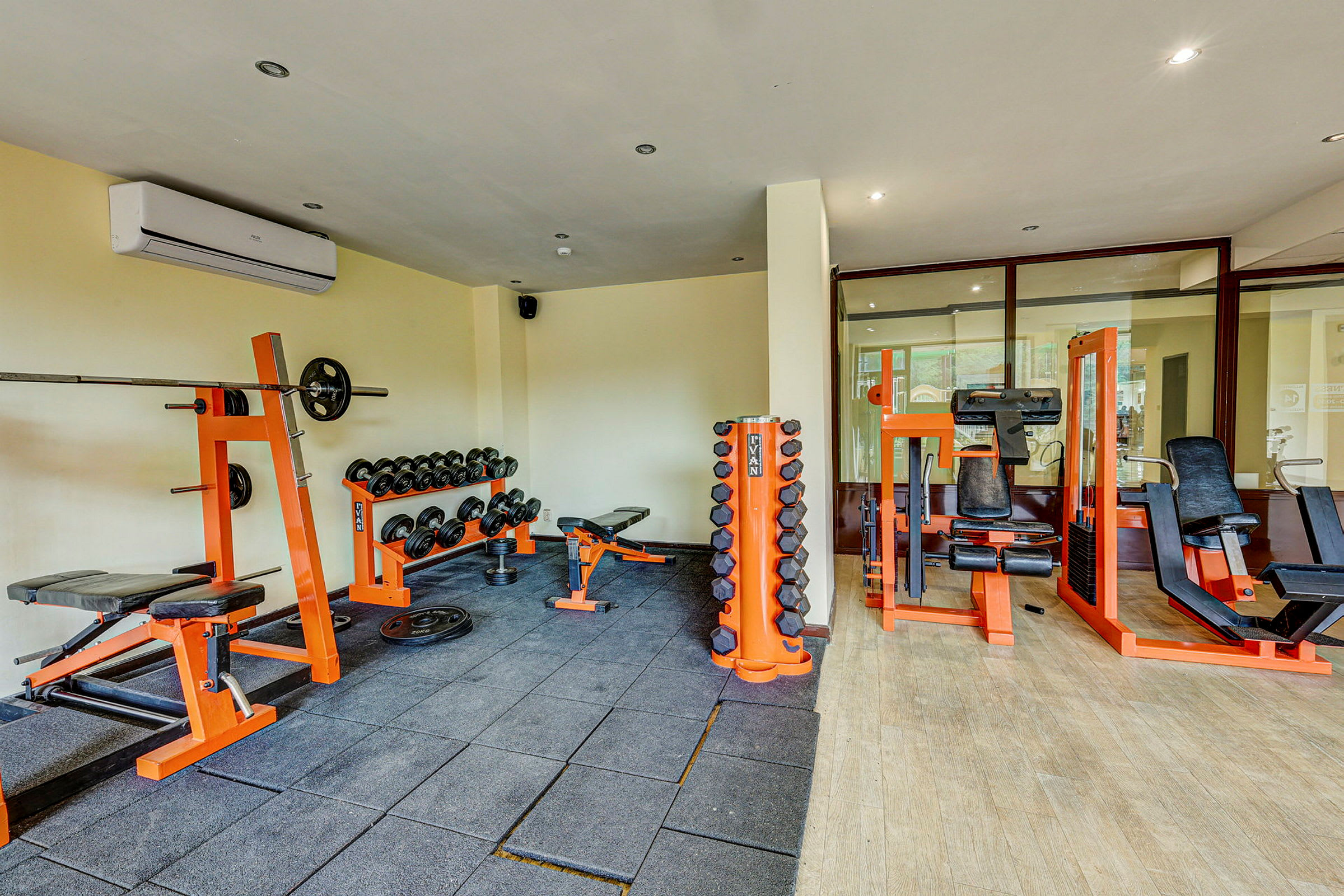 Et fitnesscenter med træningsudstyr såsom vægtstang, håndvægte og styrketræningsmaskiner. Lyse vægge og gulv. (AI-genereret tekst)