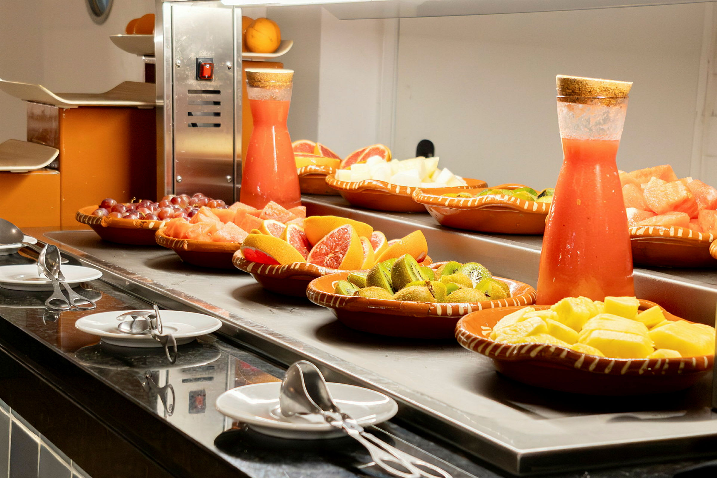Buffet med frisk frugt og juice i karaffel. (AI-genereret tekst)