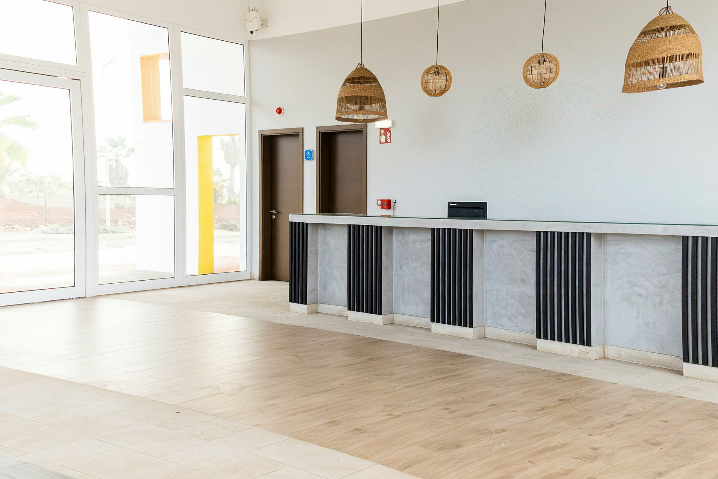 Et moderne receptionsområde med store glasvinduer og en lang skranke. (AI-genereret tekst)