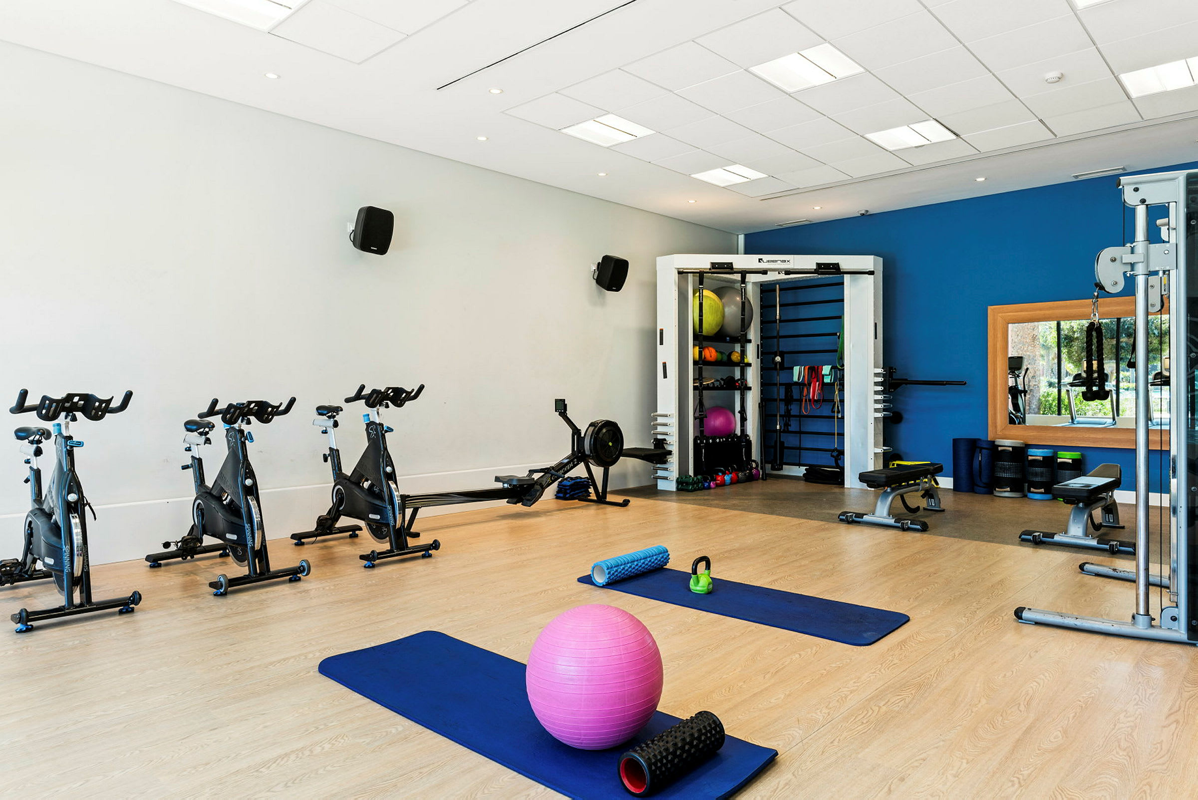 Et fitnessrum med motionscykler, yogamåtter, skumruller, medicinbolde og træningsudstyr. (AI-genereret tekst)