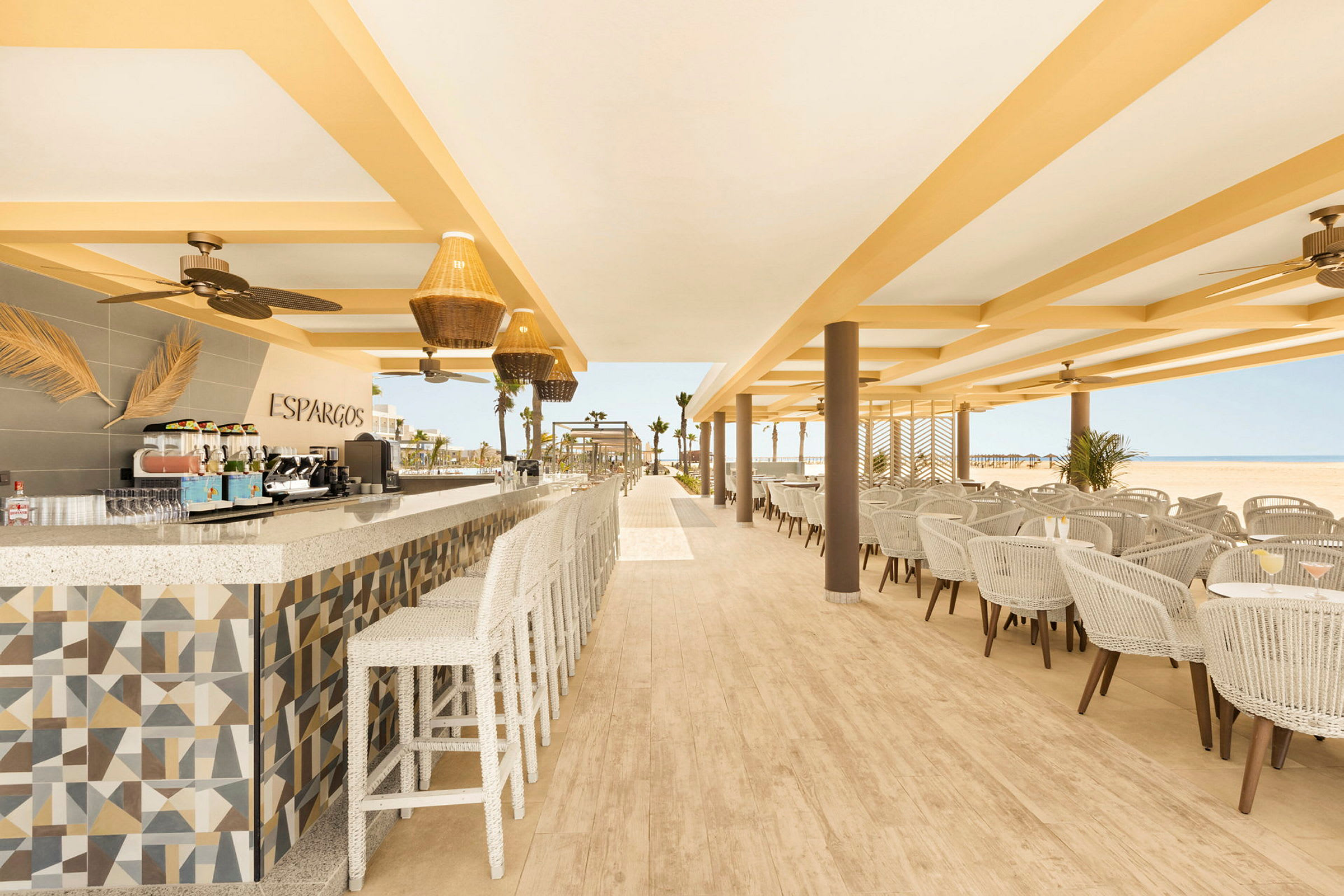 En åben og lys restaurant med siddepladser, loftsventilatorer og et veldisponeret madlavningsområde. (AI-genereret tekst)