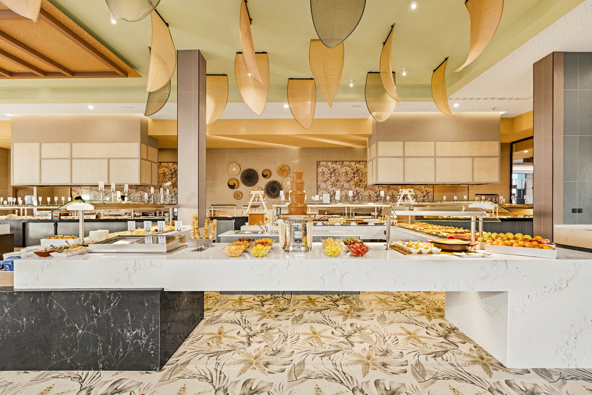 En buffet med forskellige madmuligheder, inklusive en chokoladefontæne, frugt og desserter, i en lys og moderne atmosfære. (AI-genereret tekst)