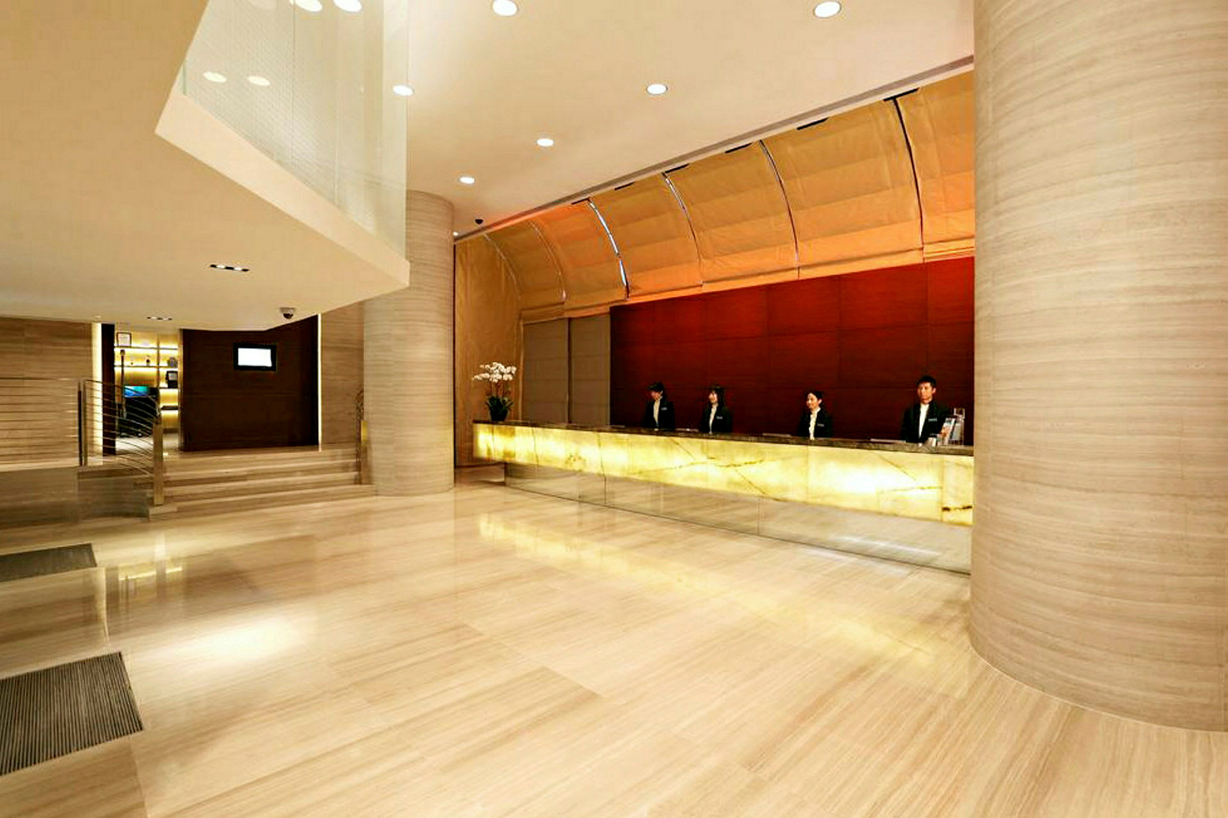 Billede af en hotelreception med en lang receptionsdisk og uniformeret personale. Gulvet er poleret sten. (AI-genereret tekst)