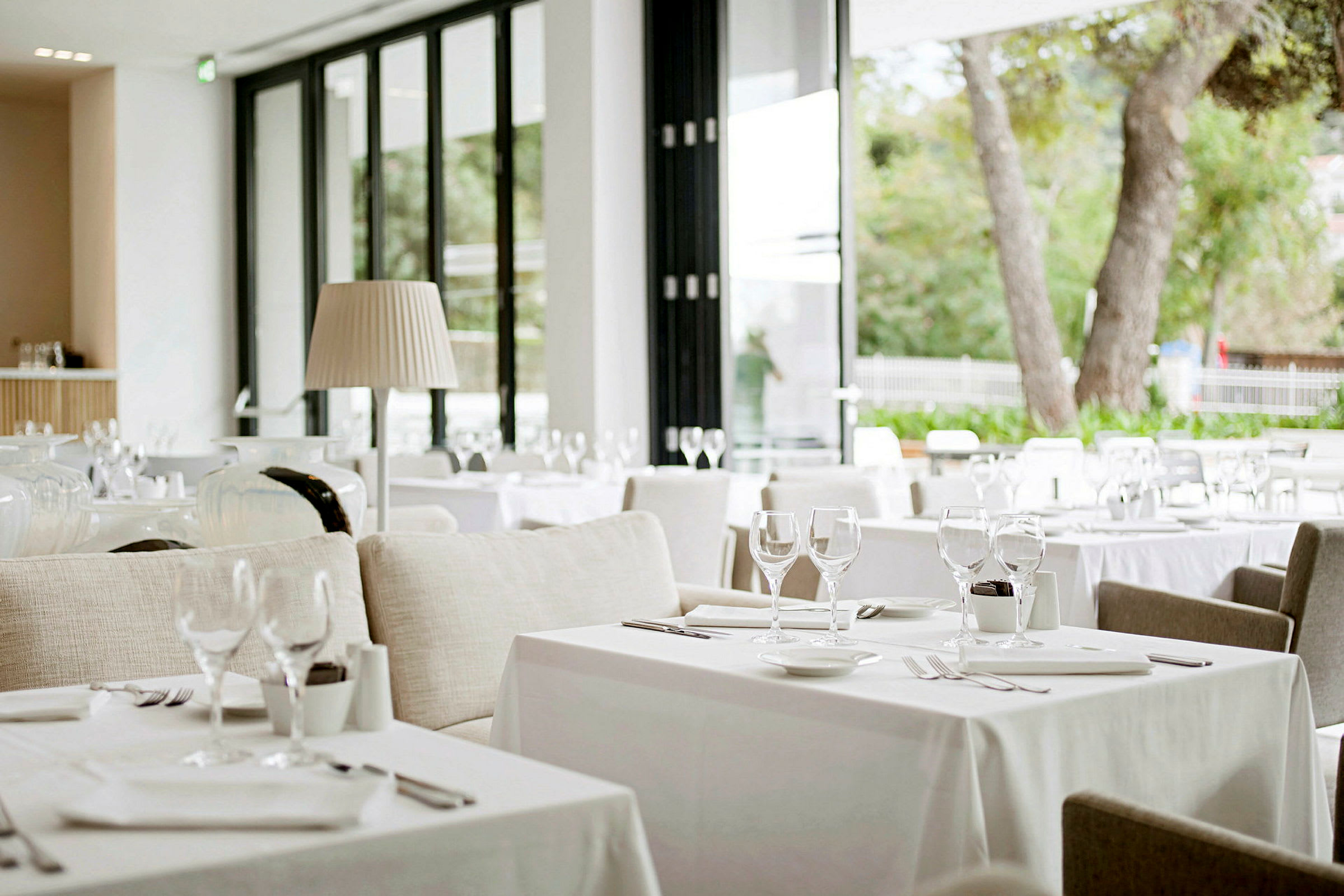 Billede af en moderne og lys restaurant med opdækkede borde og store glasvinduer, der giver naturligt lys. (AI-genereret tekst)