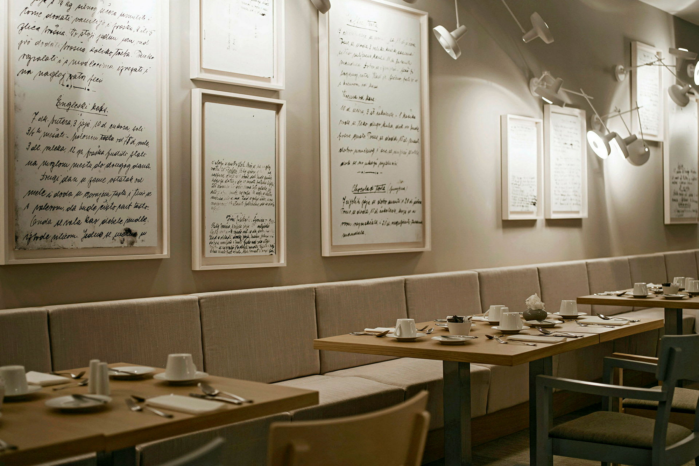 En elegant restaurant med borde opstillet til middag og dekoreret med minimalistiske billeder på væggen. (AI-genereret tekst)