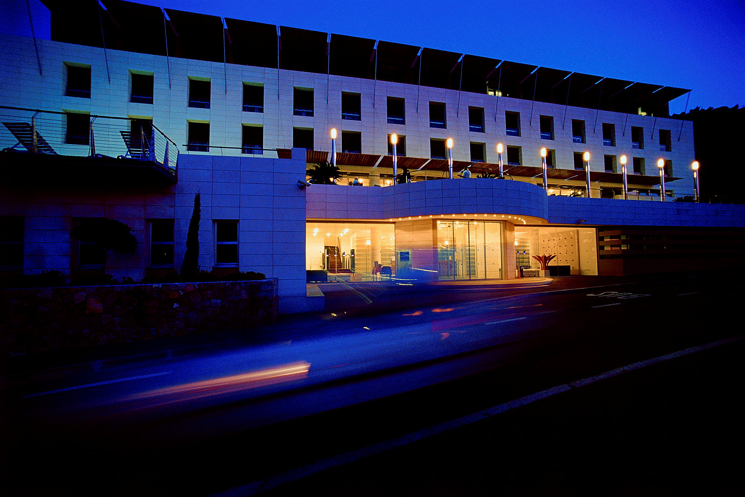 Hotellets facade oplyst i skumringen. (AI-genereret tekst)