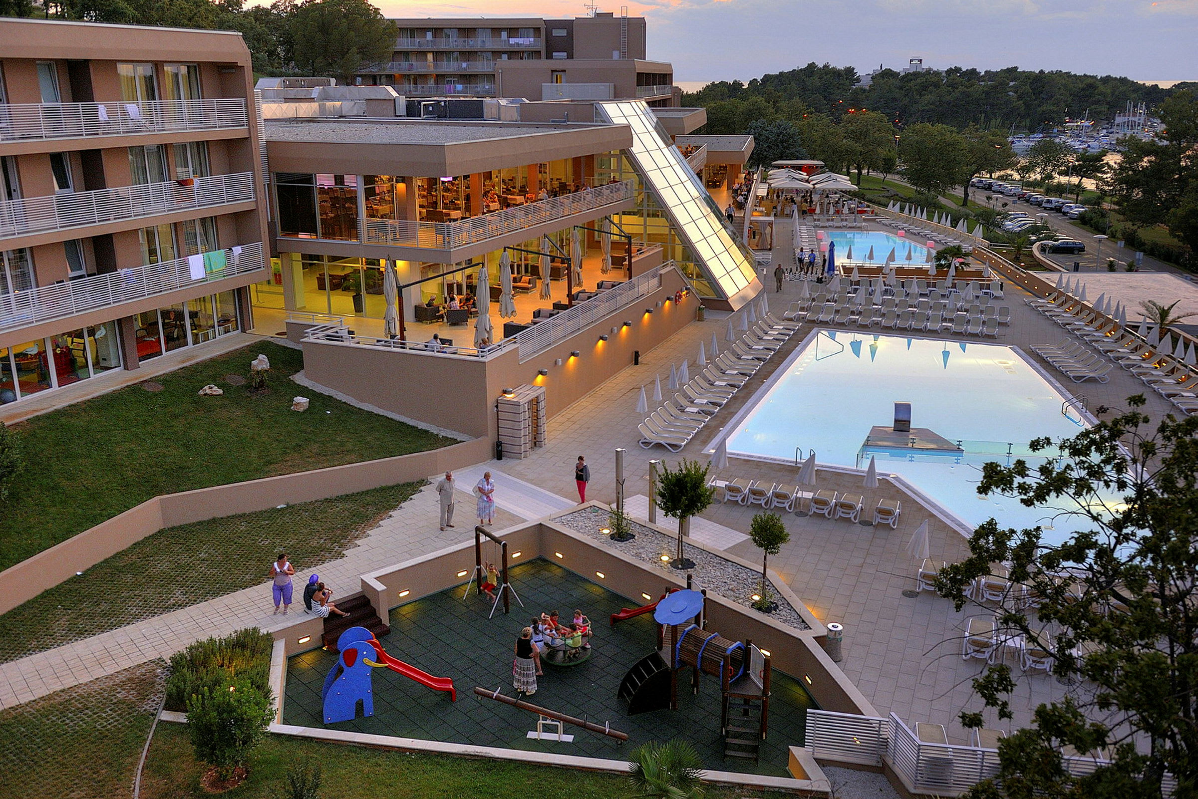 Hotellets udendørsområde med pools, solsenge og legeplads. (AI-genereret tekst)