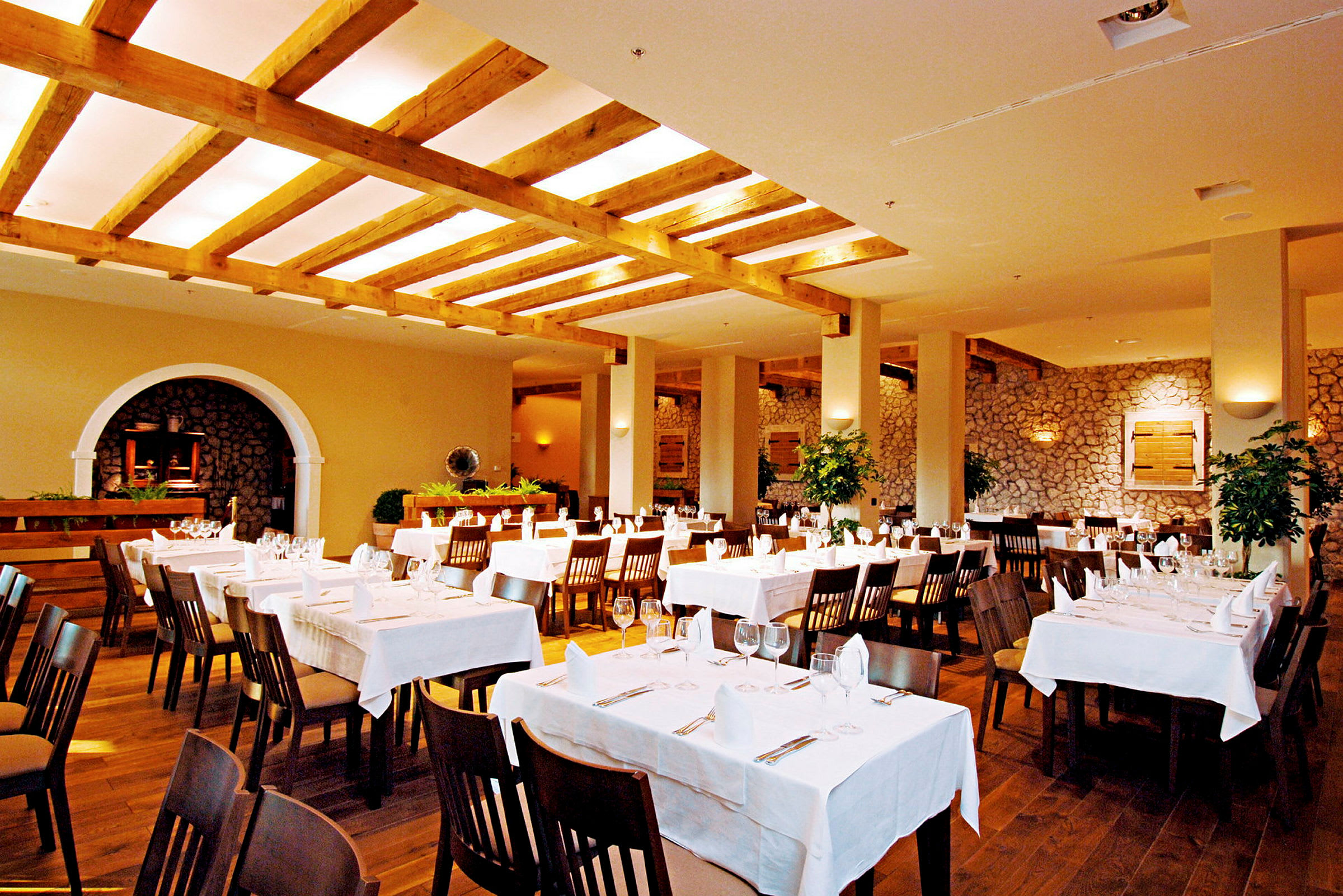 En restaurant med dækkede borde og hvide duge i et rummeligt lokale med træbjælker i loftet. (AI-genereret tekst)