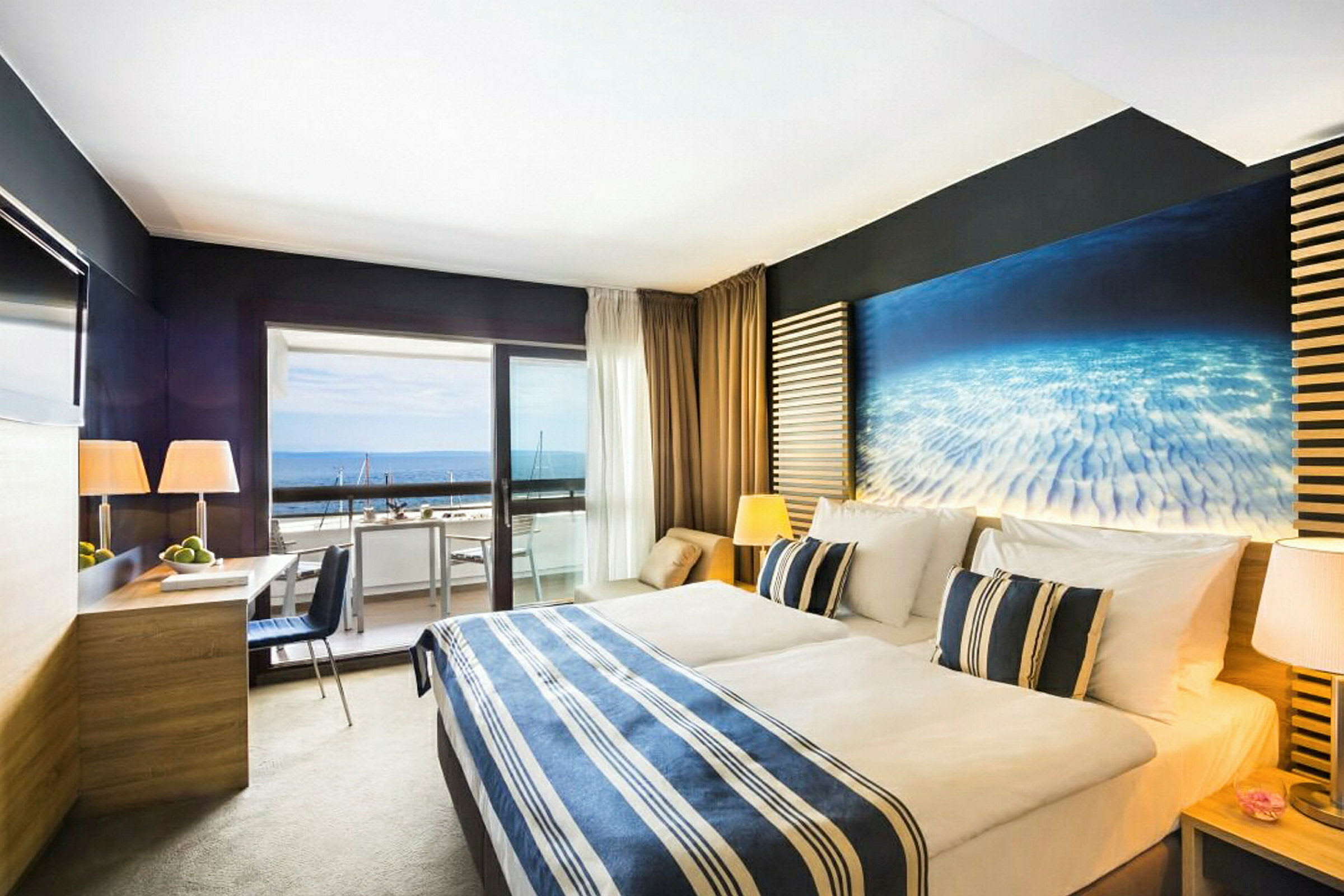 Et hotelværelse med en dobbeltseng, moderne møbler og en balkon med udsigt til havet. (AI-genereret tekst)