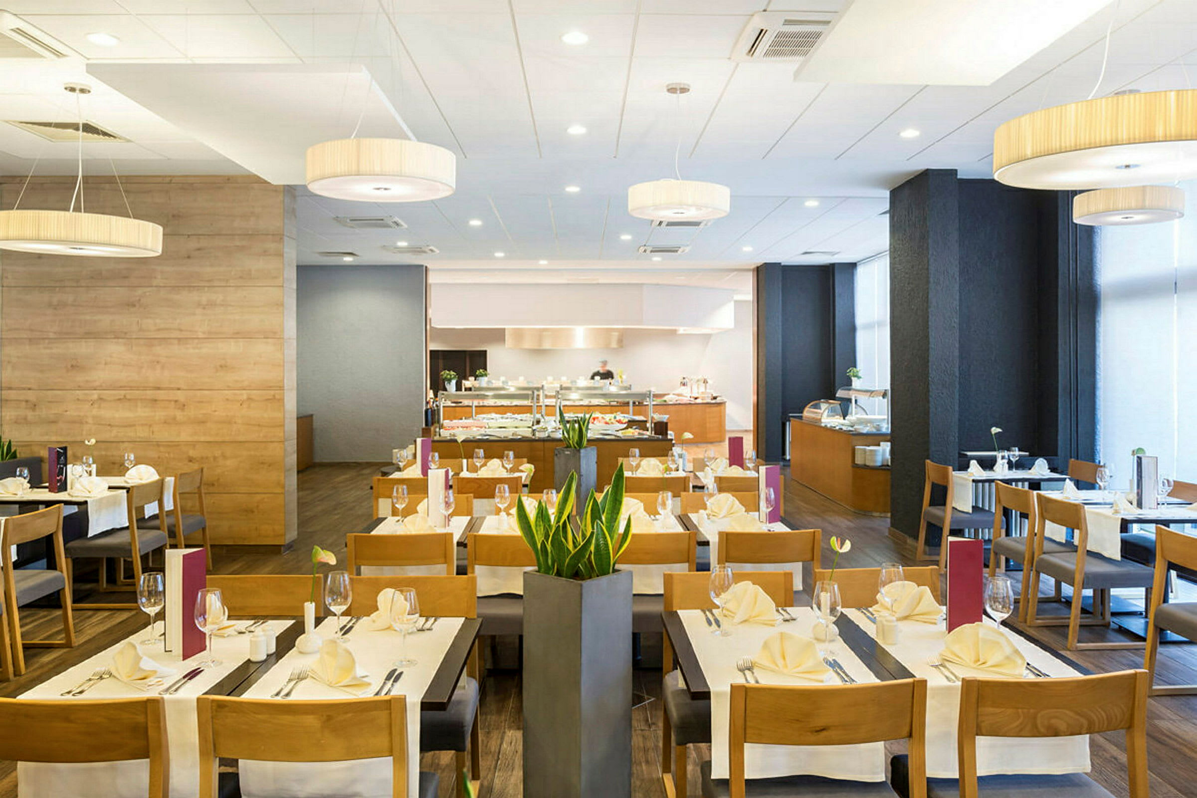 En spisestue med dækkede borde, stole og en buffet i baggrunden. (AI-genereret tekst)