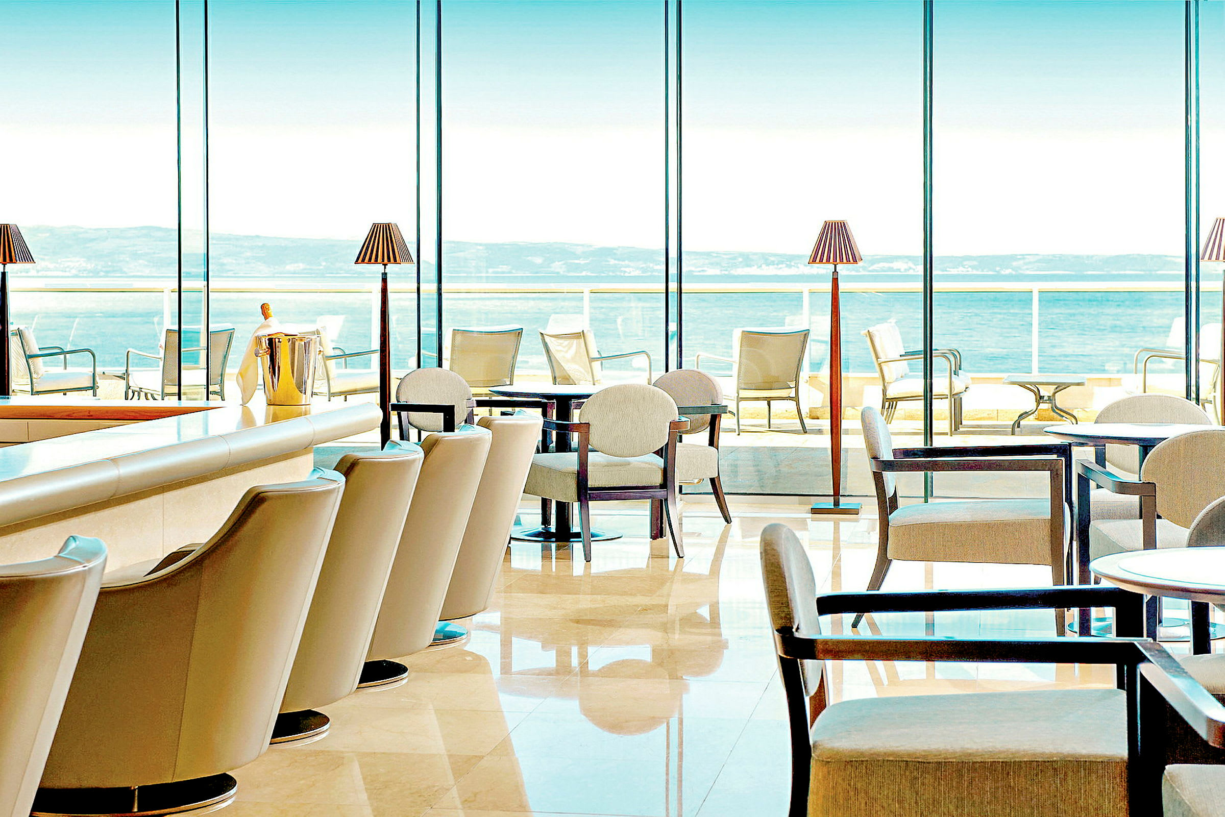 Restaurant med moderne møbler og store vinduer med udsigt over havet. (AI-genereret tekst)