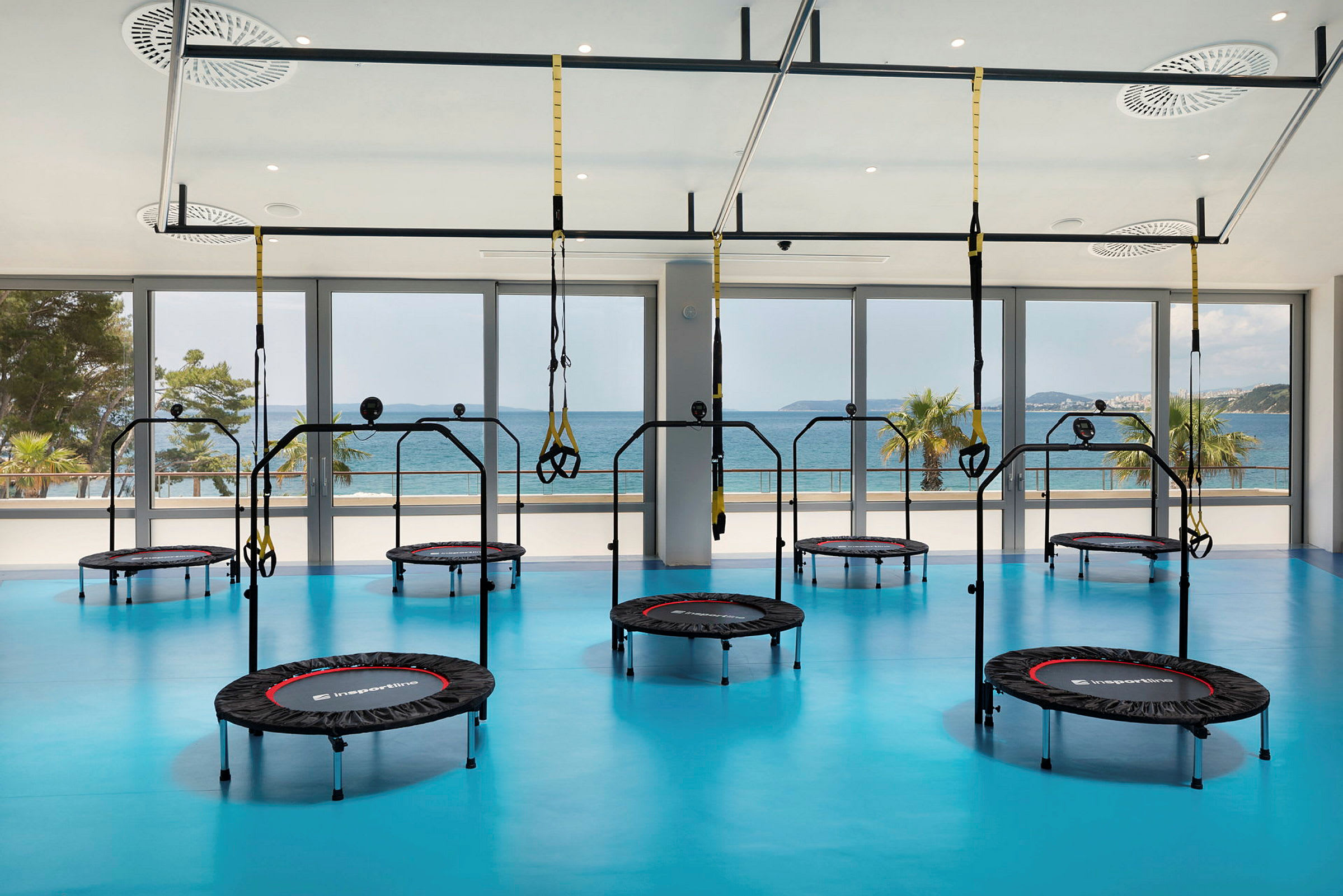Gym med trampoliner og træningsudstyr, med havudsigt. (AI-genereret tekst)