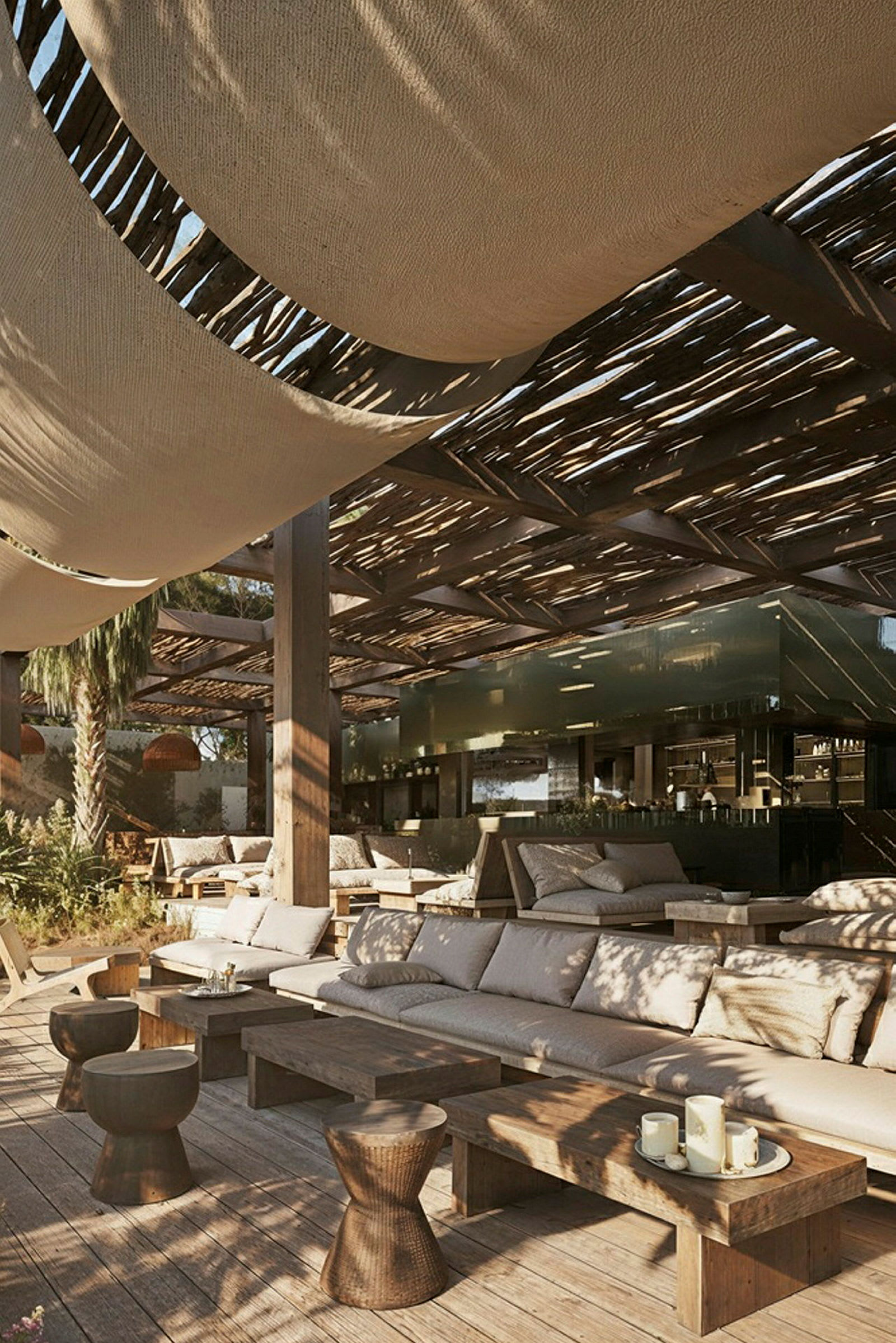 En udendørs lounge med træborde, siddepladser og skyggegørende tag. (AI-genereret tekst)