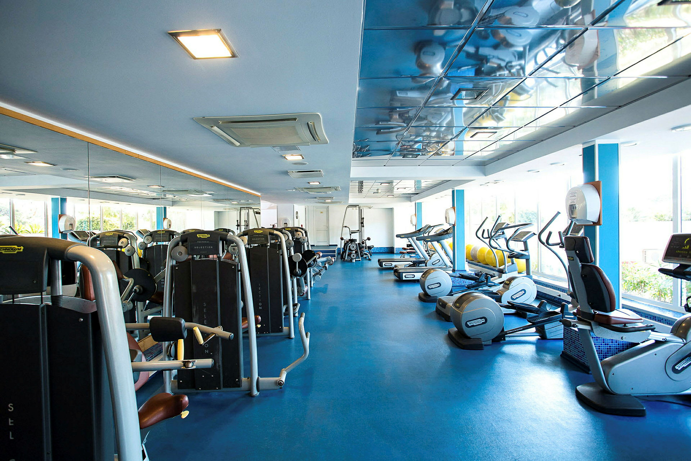 Billede af et fitnesscenter med træningsmaskiner og spejle. (AI-genereret tekst)