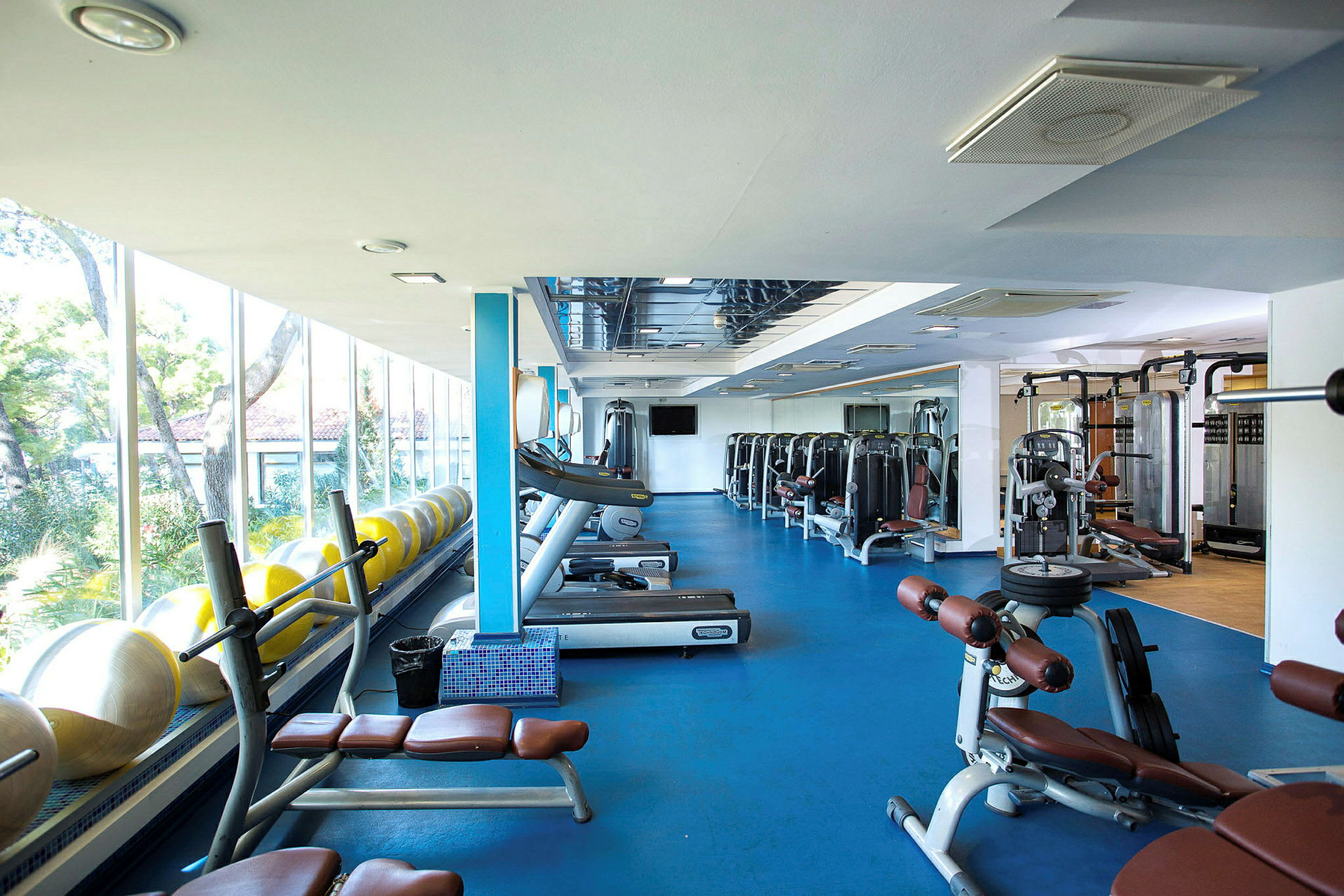 Fitnesscenter med træningsudstyr og store vinduer. (AI-genereret tekst)