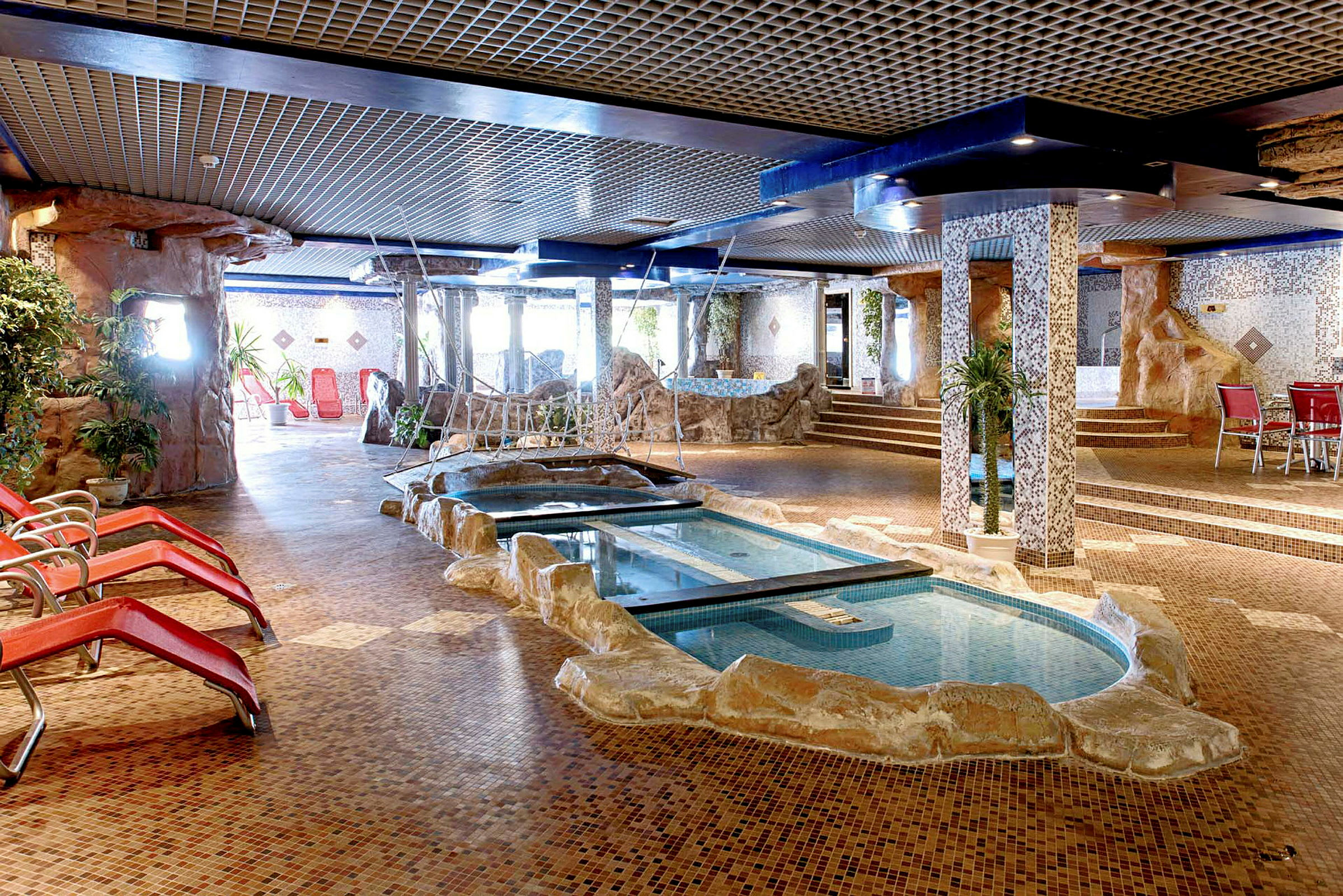 Indendørs pool med omkringliggende stole og udsmykning. (AI-genereret tekst)