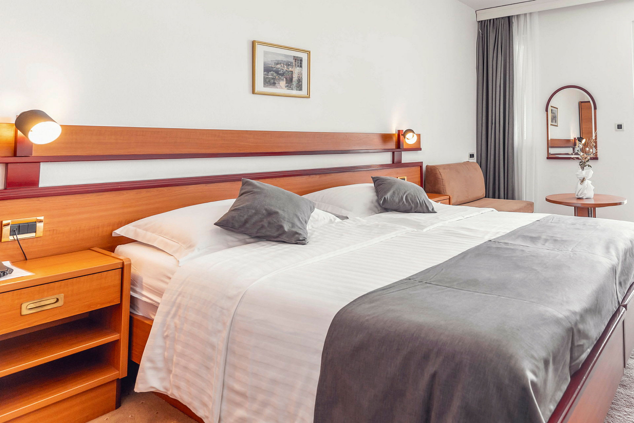 Hotelværelse med stor seng, sidebord og dekorationer. (AI-genereret tekst)
