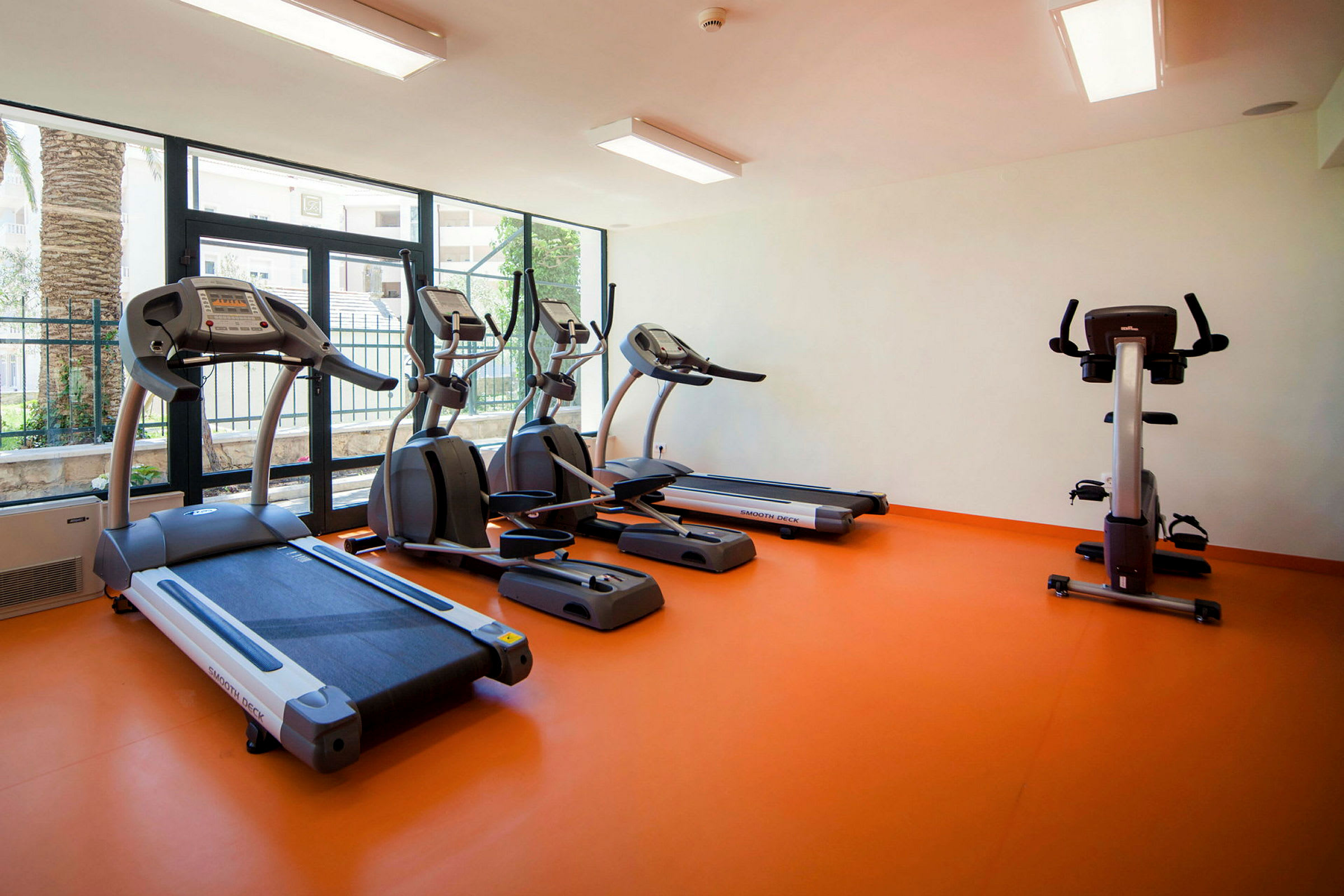 Et fitnessrum med løbebånd, motionscykel og crosstrainere. (AI-genereret tekst)