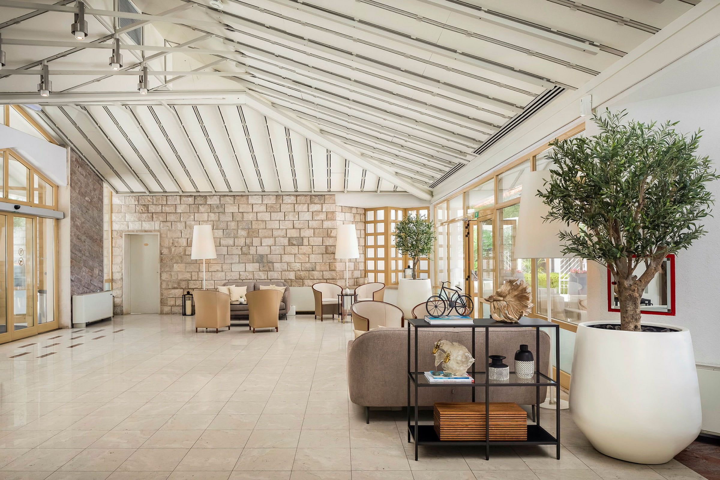 Lys og rummelig hotellobby med siddeområder og dekorative planter. (AI-genereret tekst)