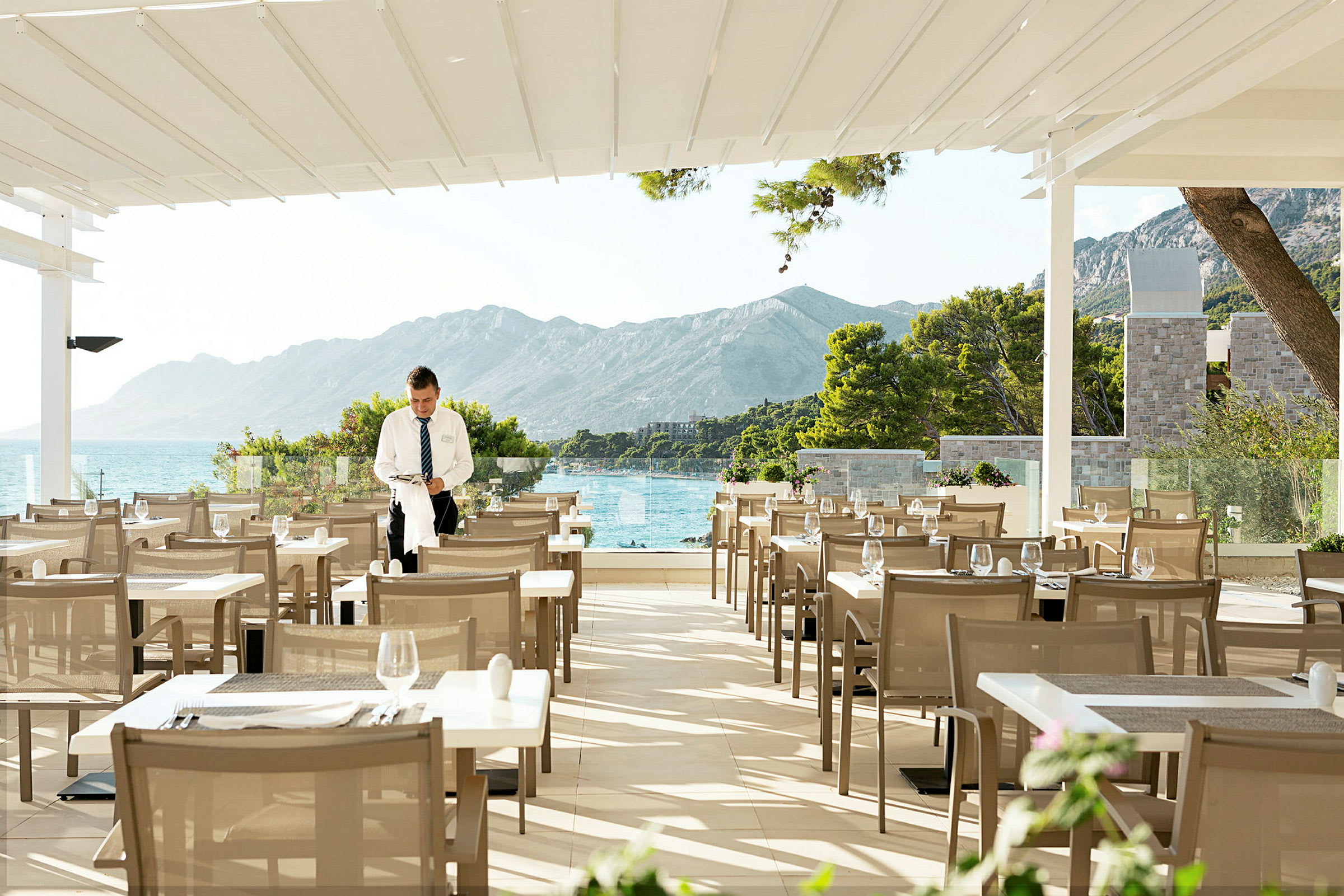 Restaurantterrasse med udsigt over havet og bjergene. (AI-genereret tekst)