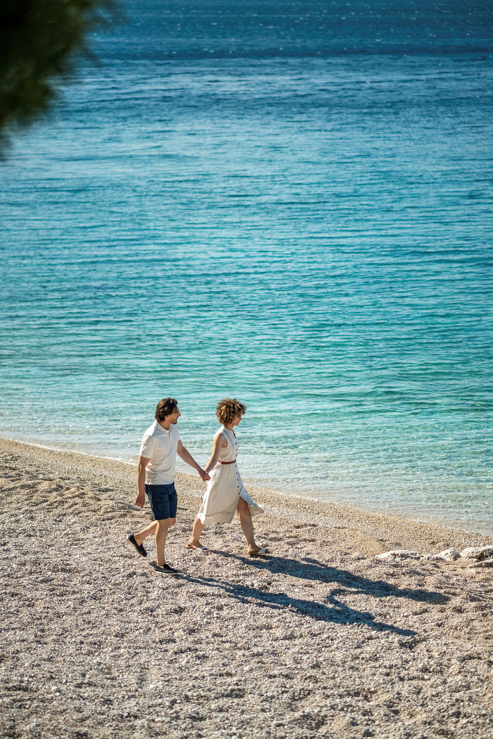 To personer går på en stenstrand ved havet. (AI-genereret tekst)