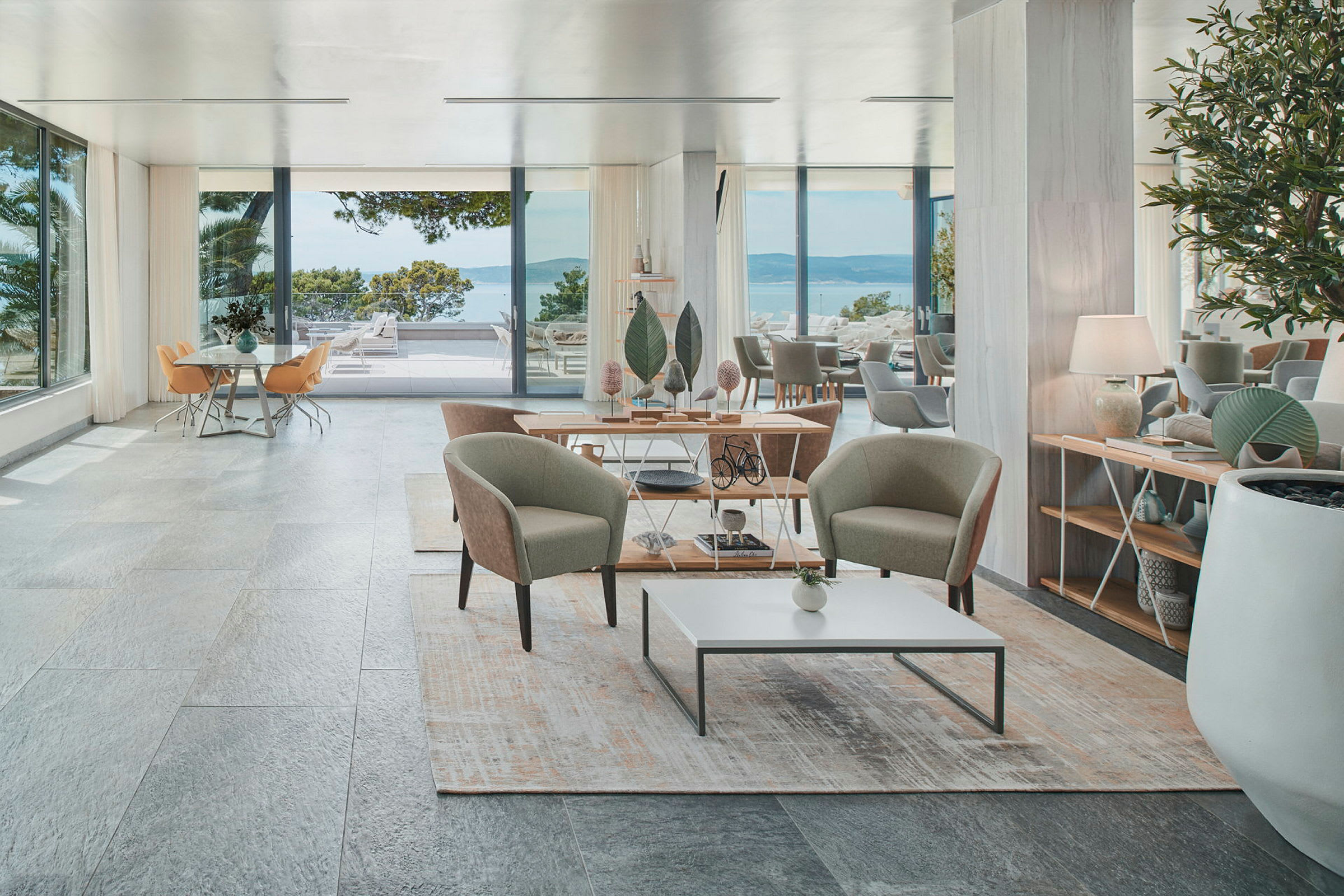 Et elegant hotelværelse med siddeområde, store vinduer og udsigt over havet. (AI-genereret tekst)