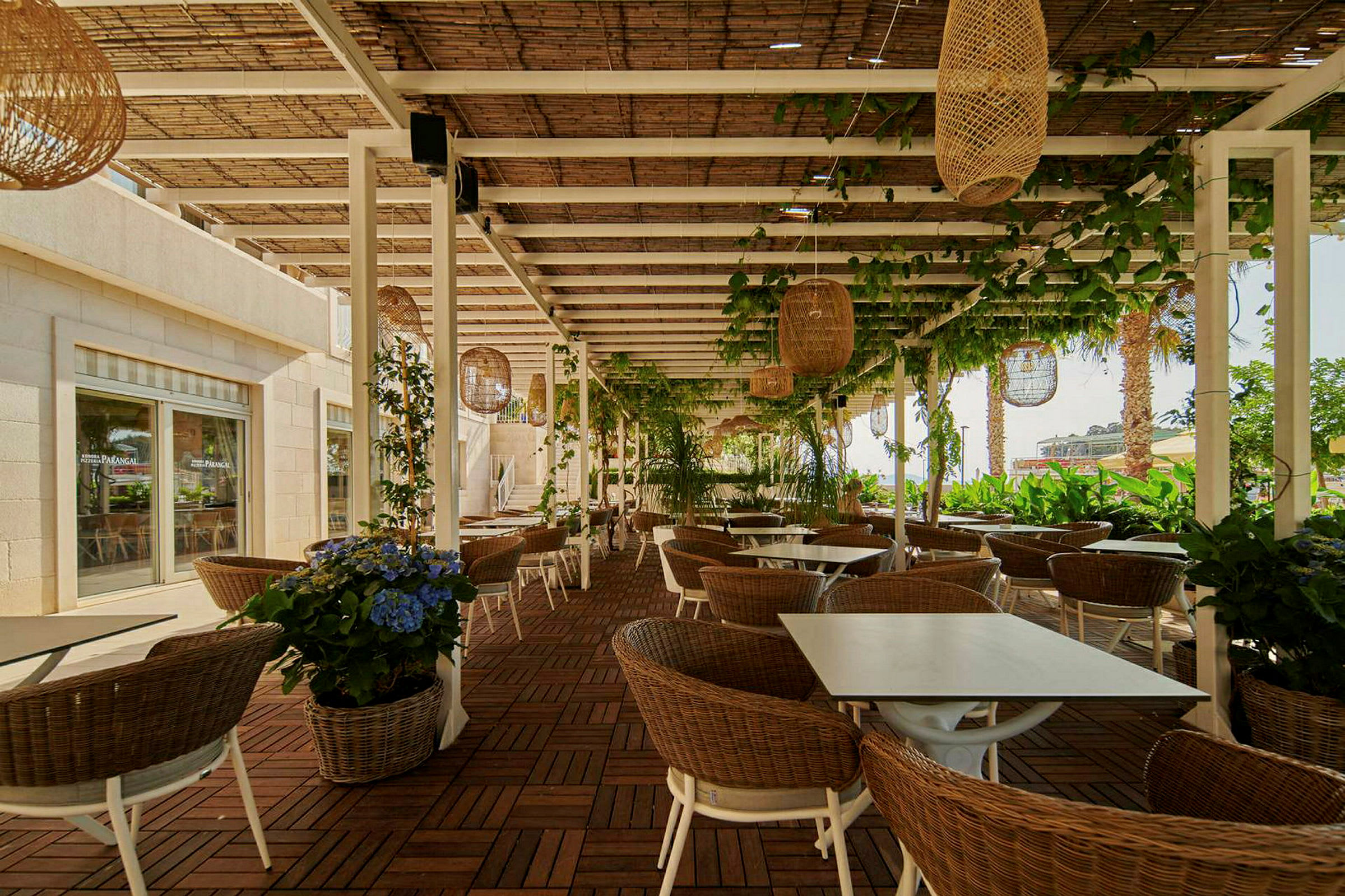 Udendørs servering med borde, stole og planter under en pergola. (AI-genereret tekst)