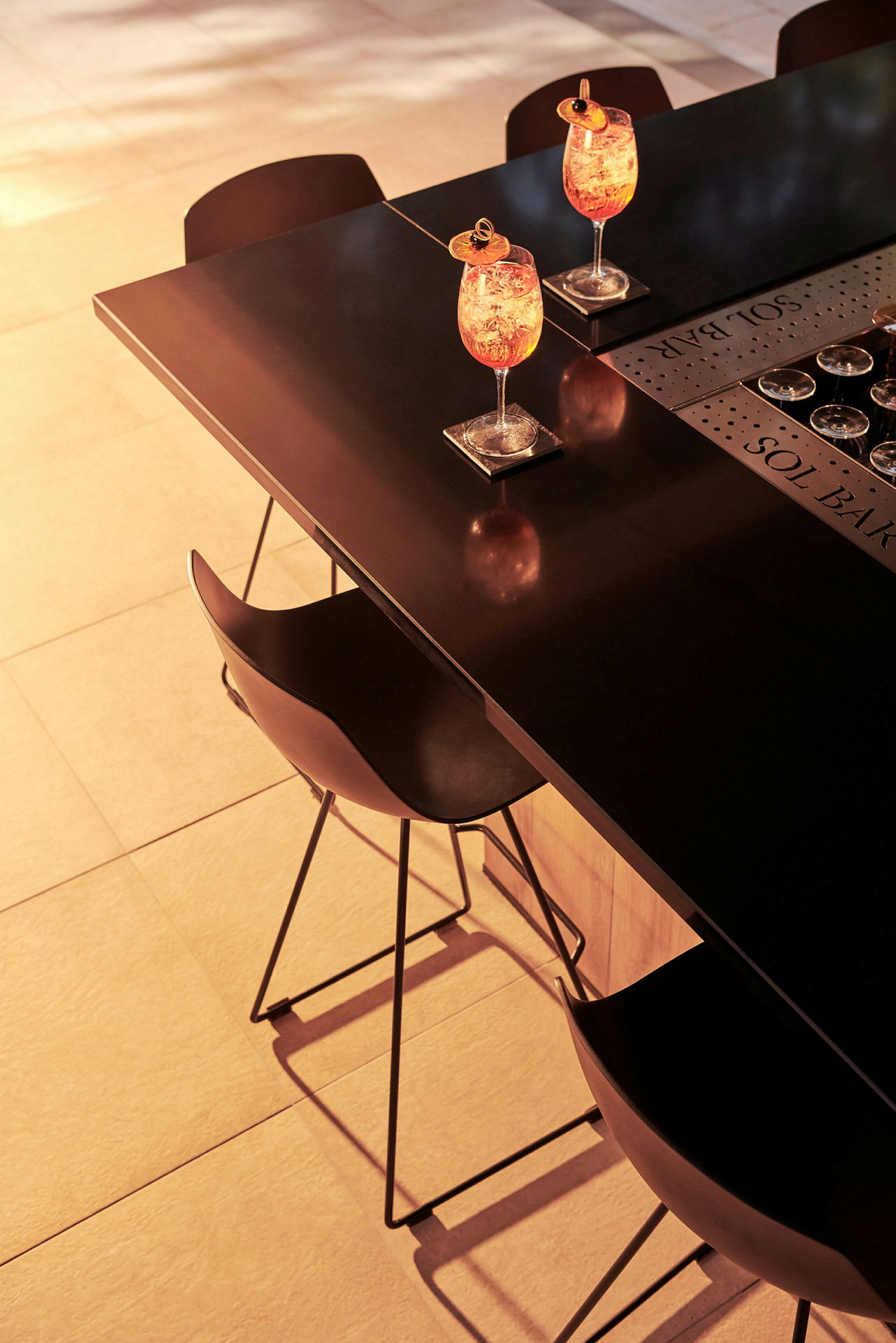 To cocktails på et bord med stole i aftenslys. (AI-genereret tekst)