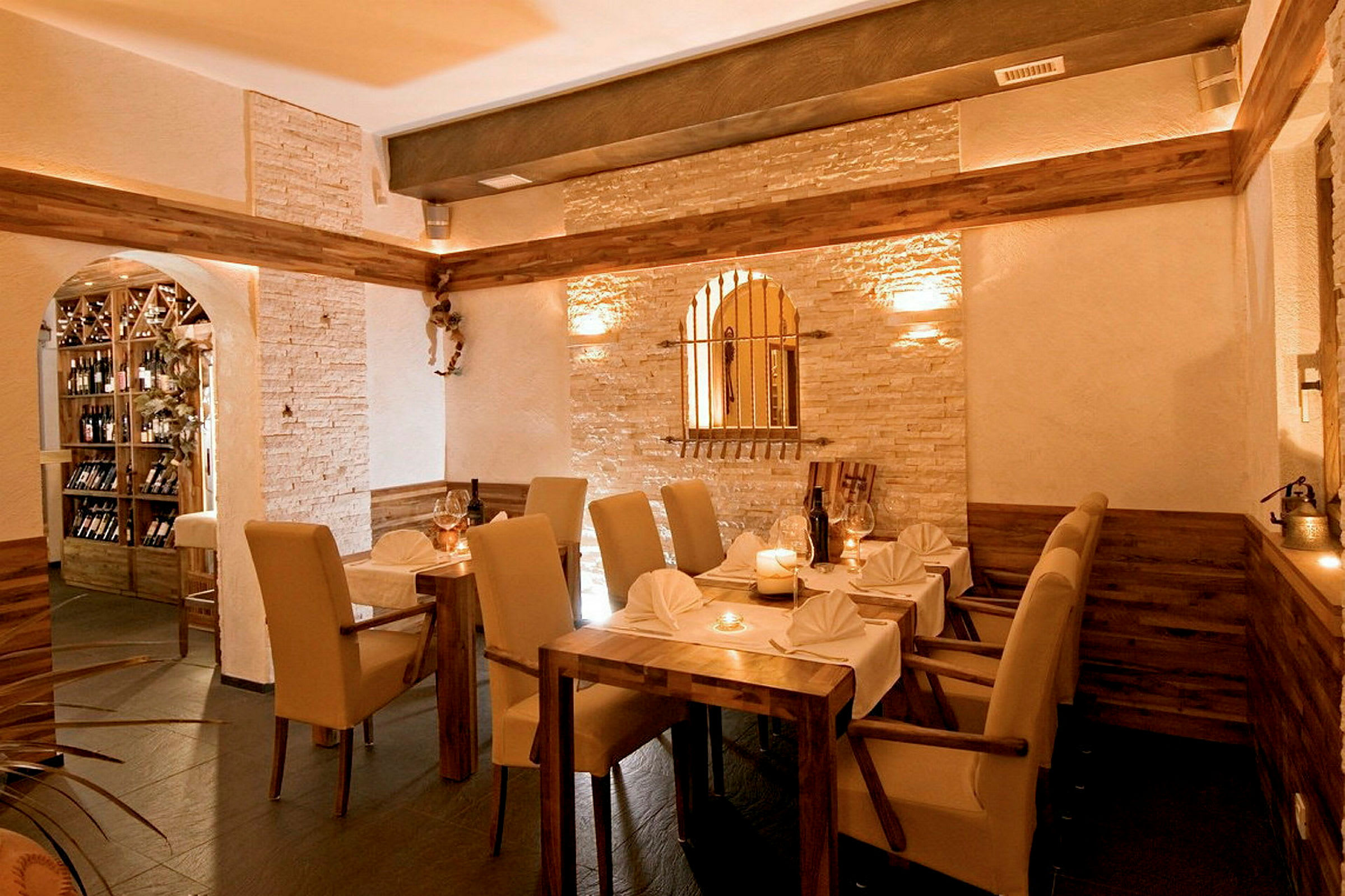 Interiør af en restaurant med et bord og stole samt stenvægge og trædetaljer. (AI-genereret tekst)