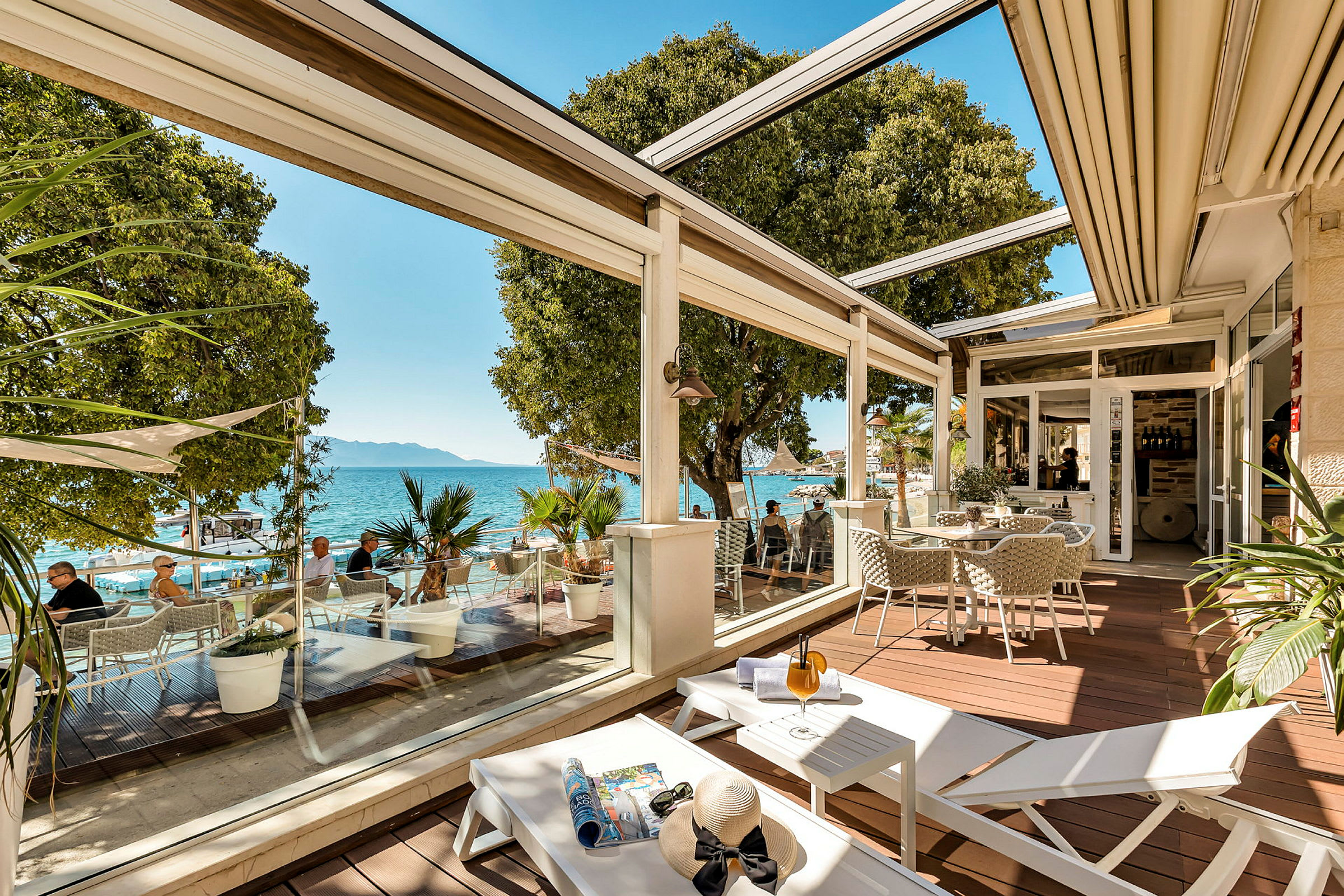En terrasse med siddepladser, liggestole og udsigt over havet. (AI-genereret tekst)