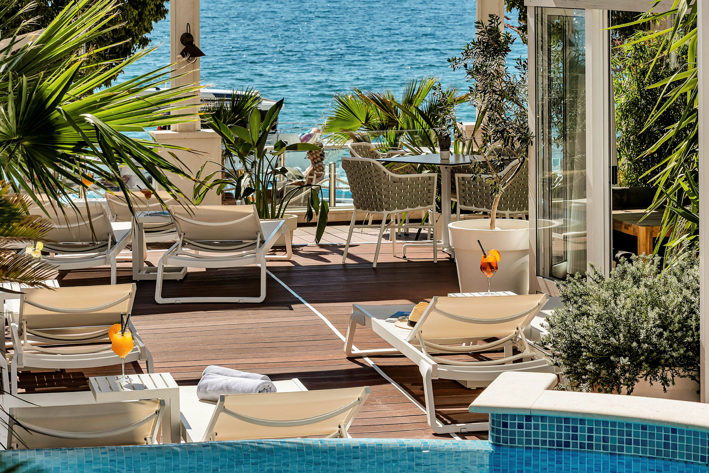 Liggestole og borde på en balkon med udsigt over havet. (AI-genereret tekst)