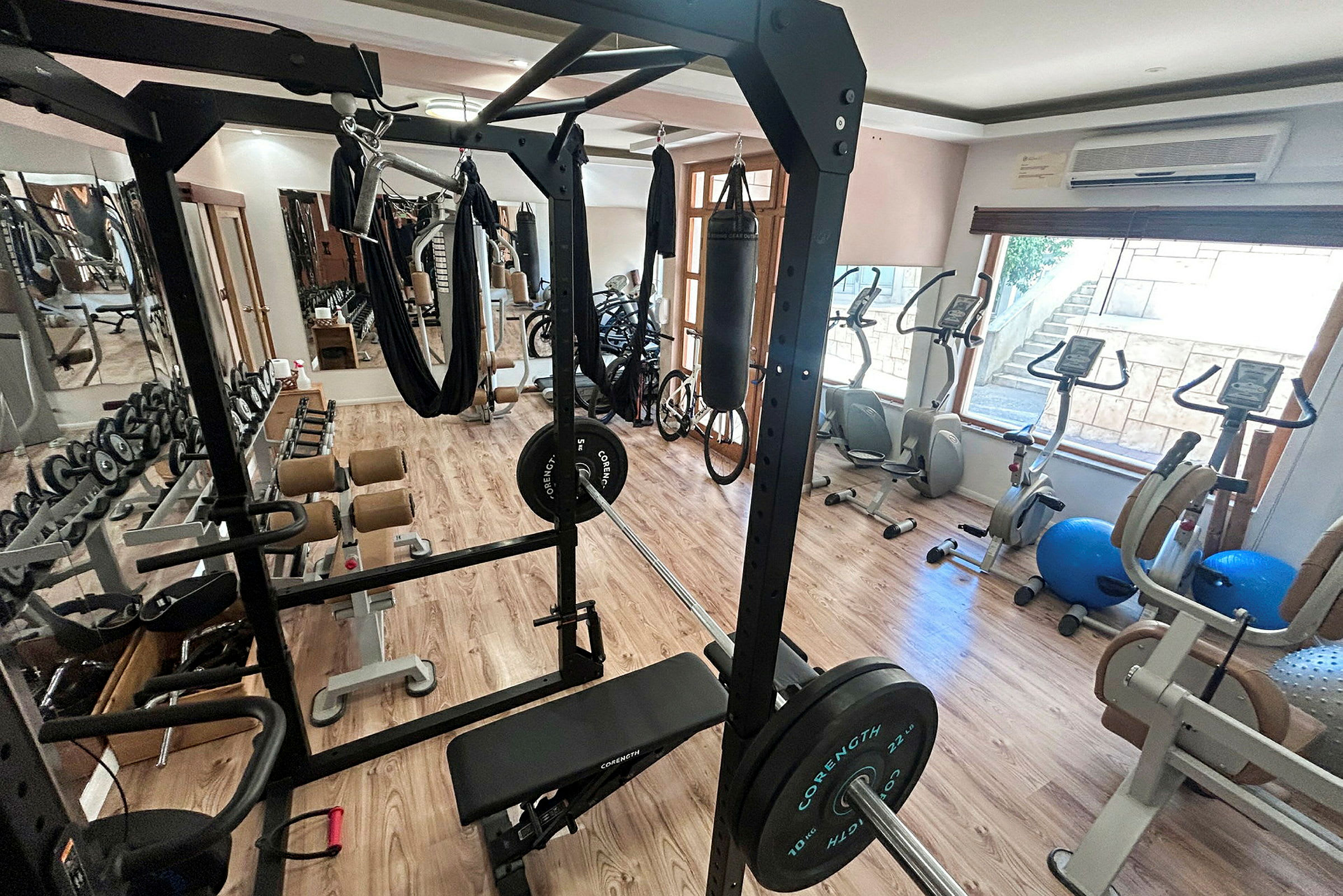 Billede af et fitnesscenter med træningsudstyr såsom et squatstativ, vægte og motionscykler. (AI-genereret tekst)