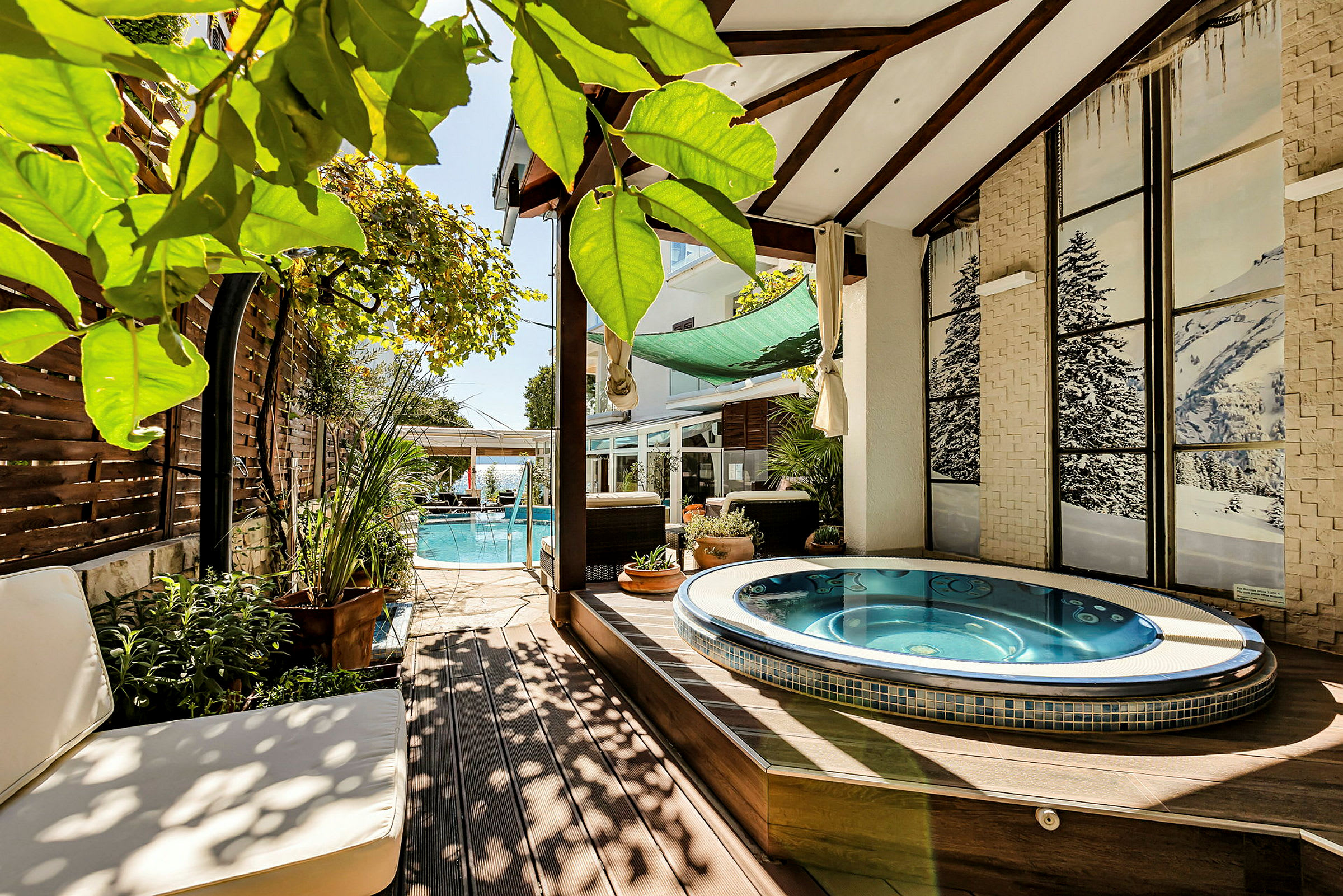Udendørs miljø med jacuzzi og en pool samt grønne planter. (AI-genereret tekst)
