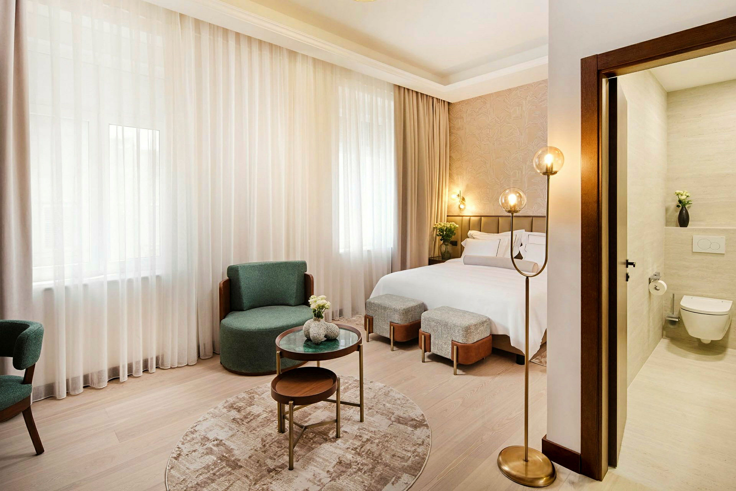 Et moderne hotelværelse med en dobbeltseng, stole, sofabord og en delvist synlig badeværelsesdel. (AI-genereret tekst)