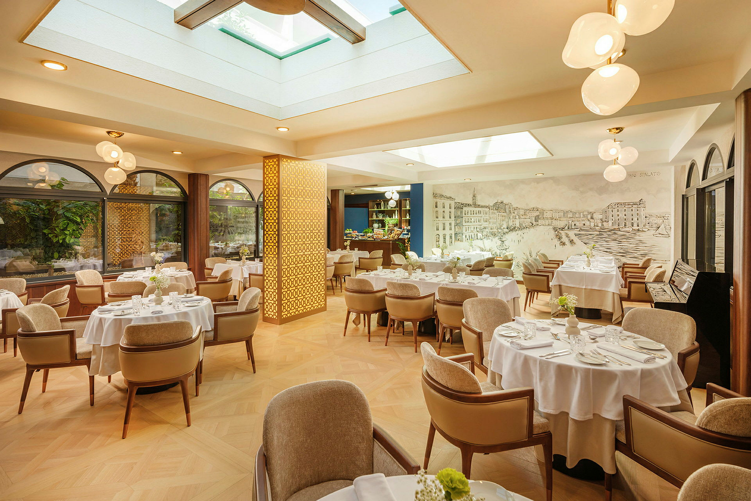 En lys og elegant restaurant med borde med hvide duge og komfortable stole. Vinduer med planter udenfor og ovenlys giver naturligt lys. (AI-genereret tekst)