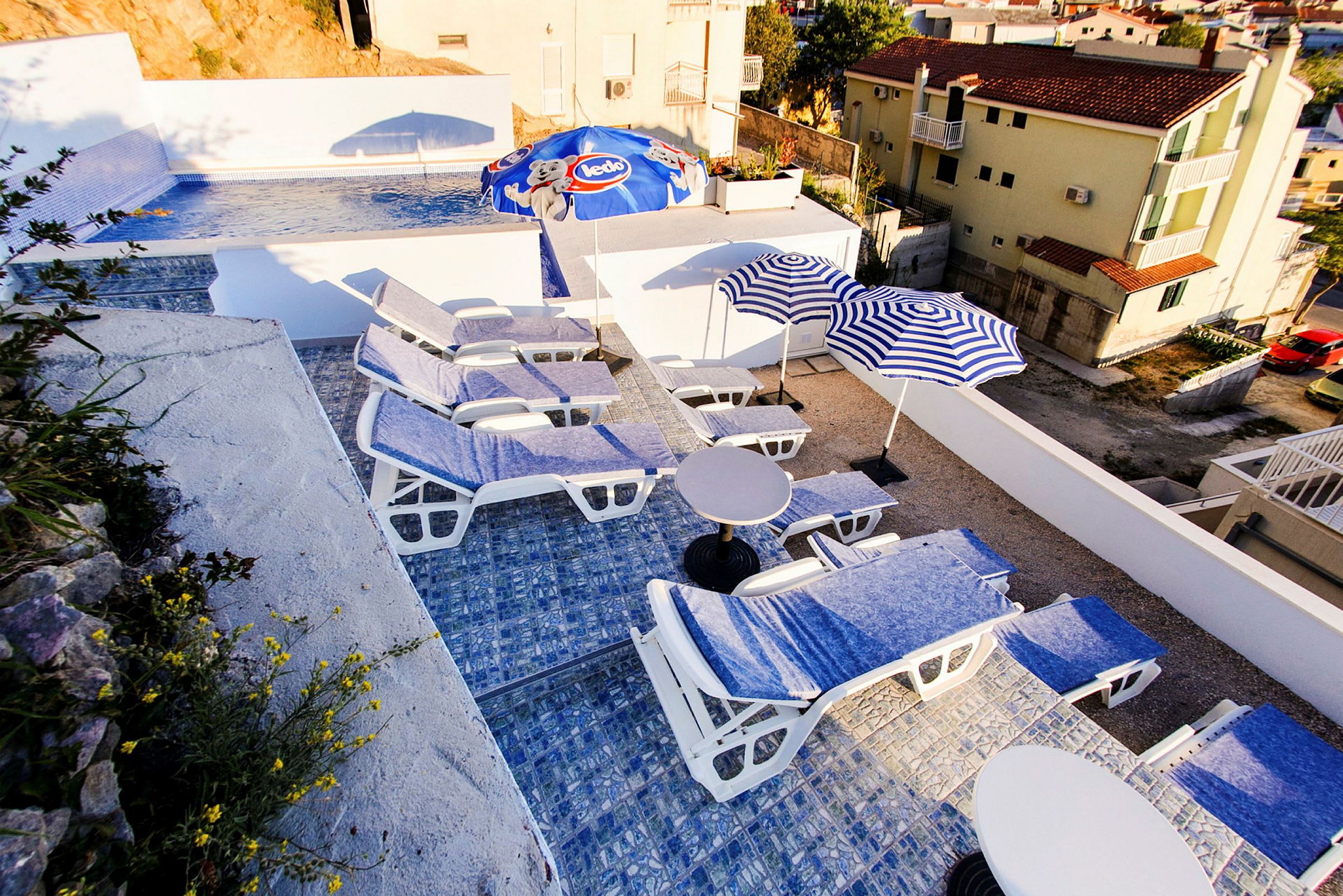 En udendørs pool og liggestole med parasoller på en terrasse. (AI-genereret tekst)