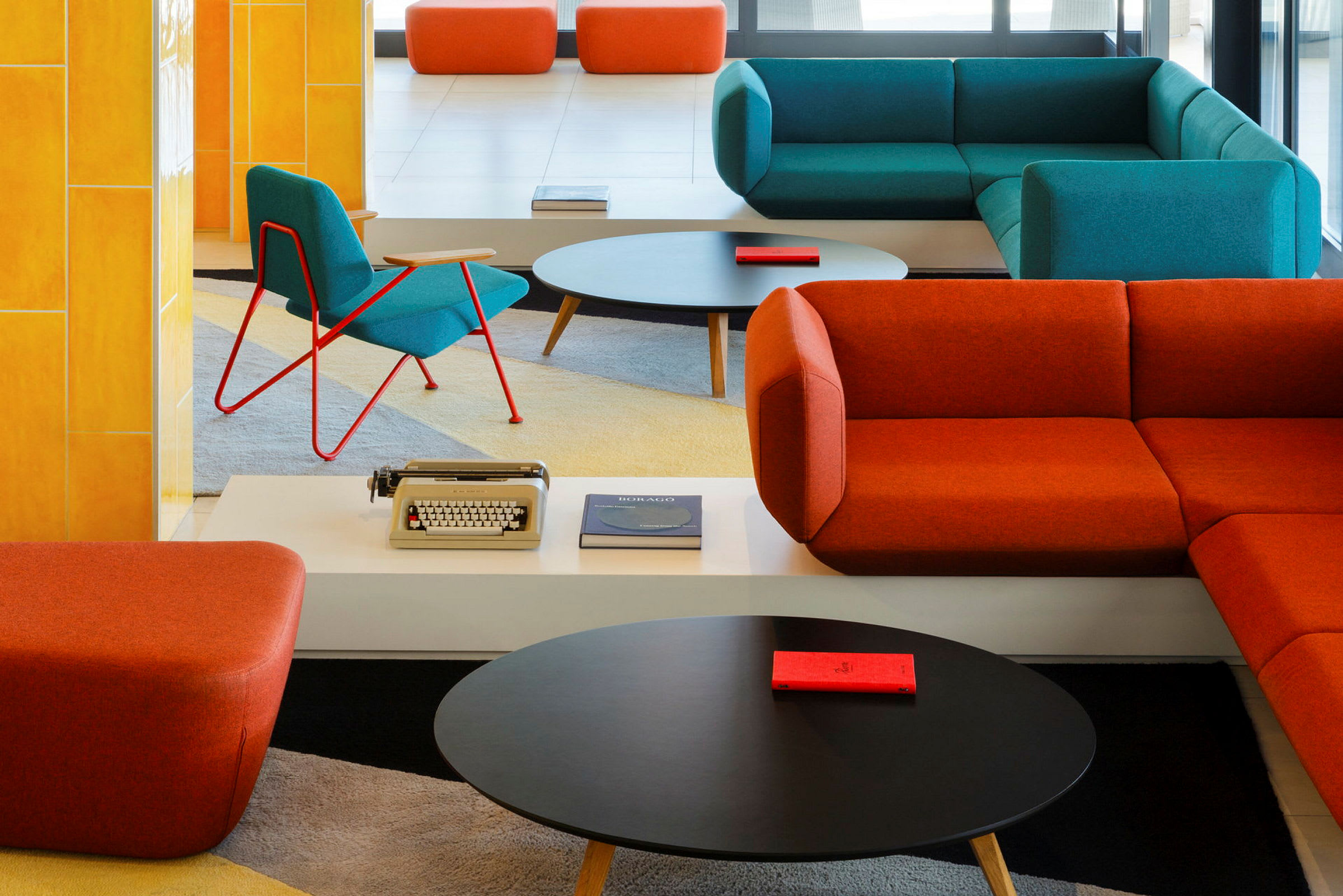 Interiørbillede af en moderne lounge med farverige sofaer og stole, et sofabord og dekorative elementer. (AI-genereret tekst)