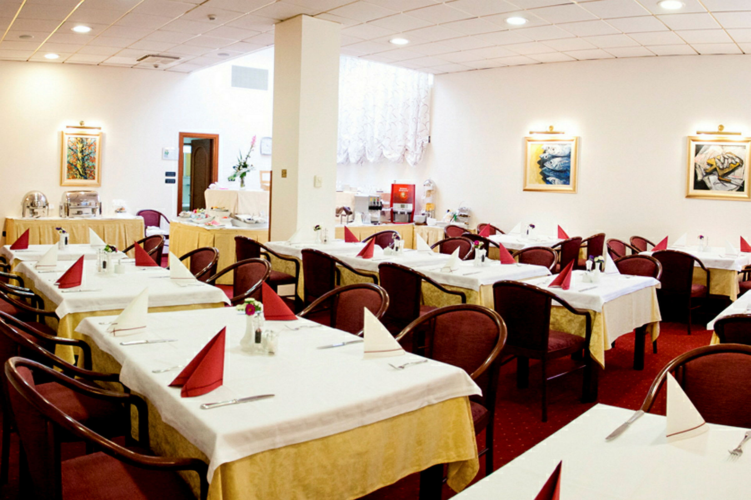 En restaurantindretning med flere opstillede borde, hver udstyret med foldede servietter og stole samt dekorationer som malerier og væglamper. (AI-genereret tekst)