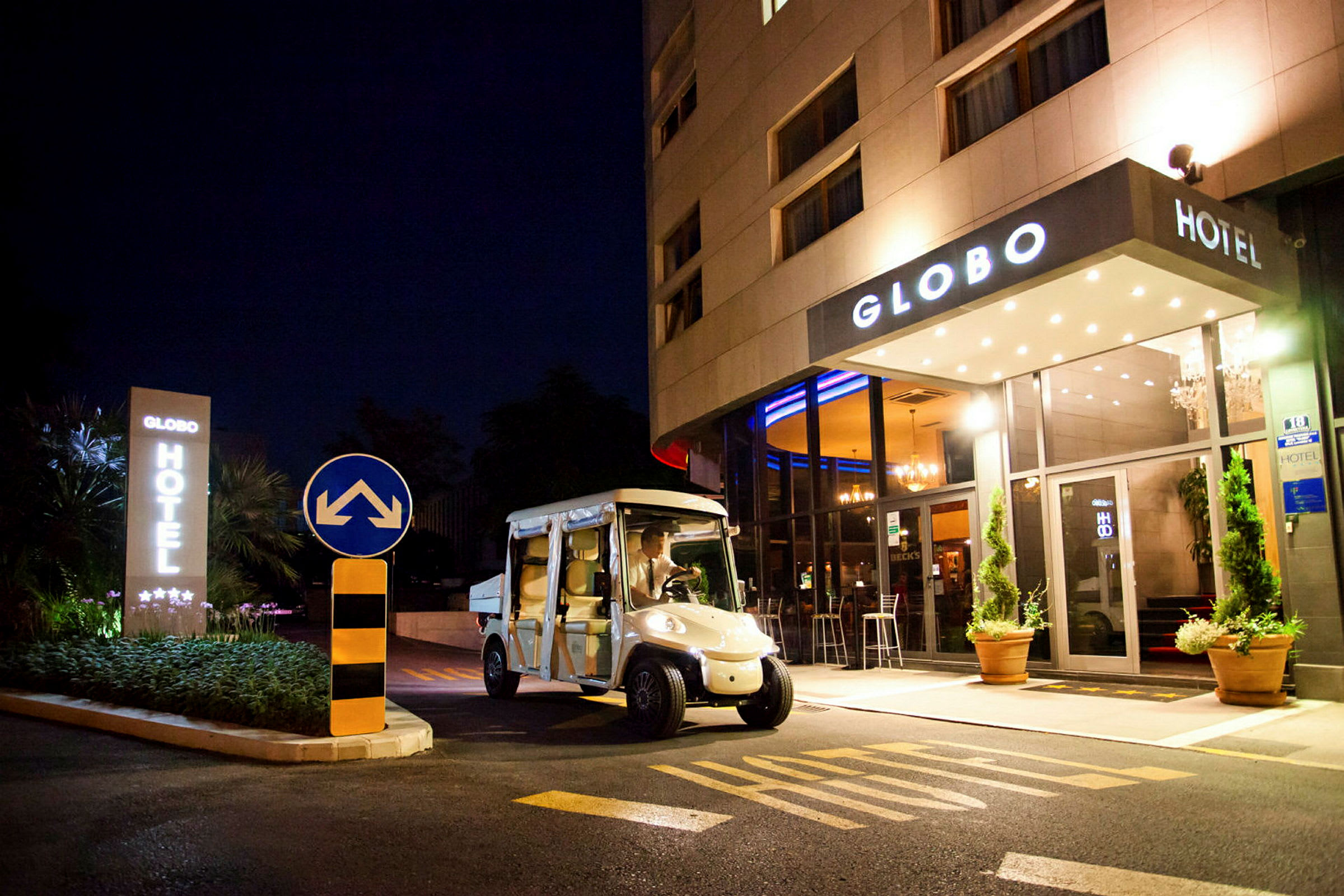 Et hotel set om natten med navnet Globo, en elbil er parkeret foran indgangen. (AI-genereret tekst)