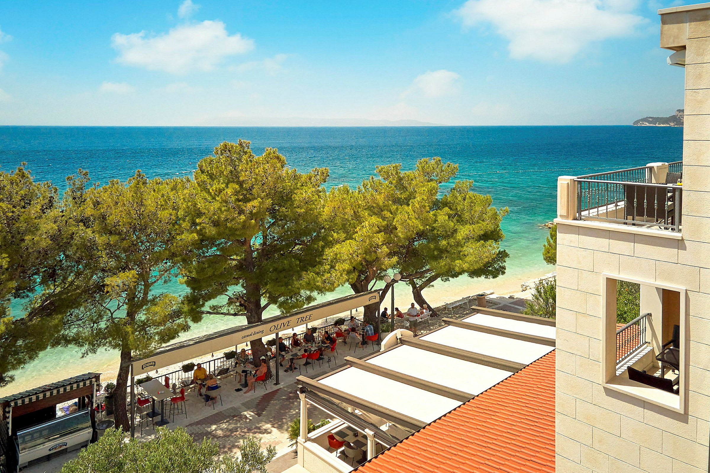 Udsigt over en restaurant ved stranden med havet i baggrunden. (AI-genereret tekst)