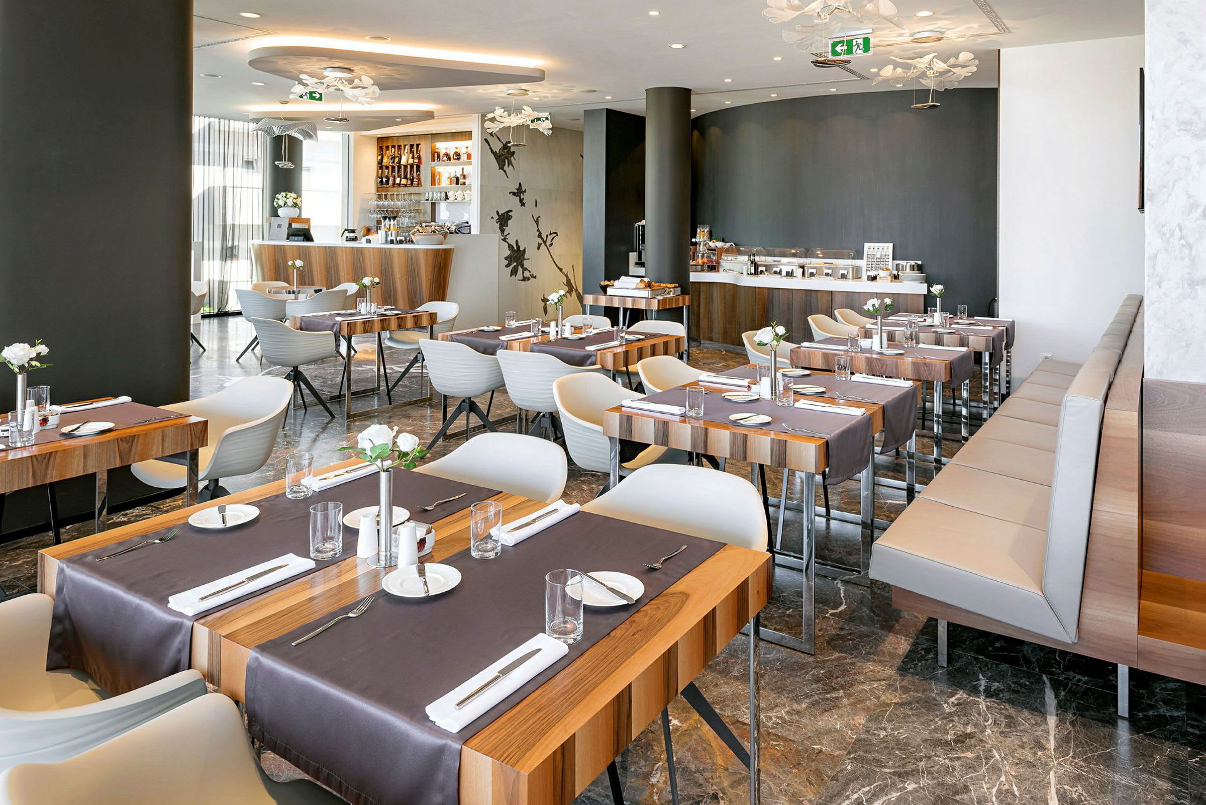 Et moderne restaurantområde med træborde og hvide stole, dækket til måltider. (AI-genereret tekst)