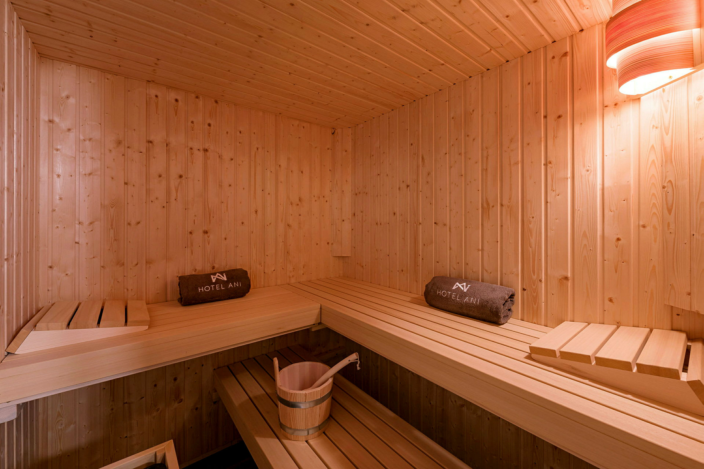 En træindrettet sauna med siddepladser og en spand. (AI-genereret tekst)