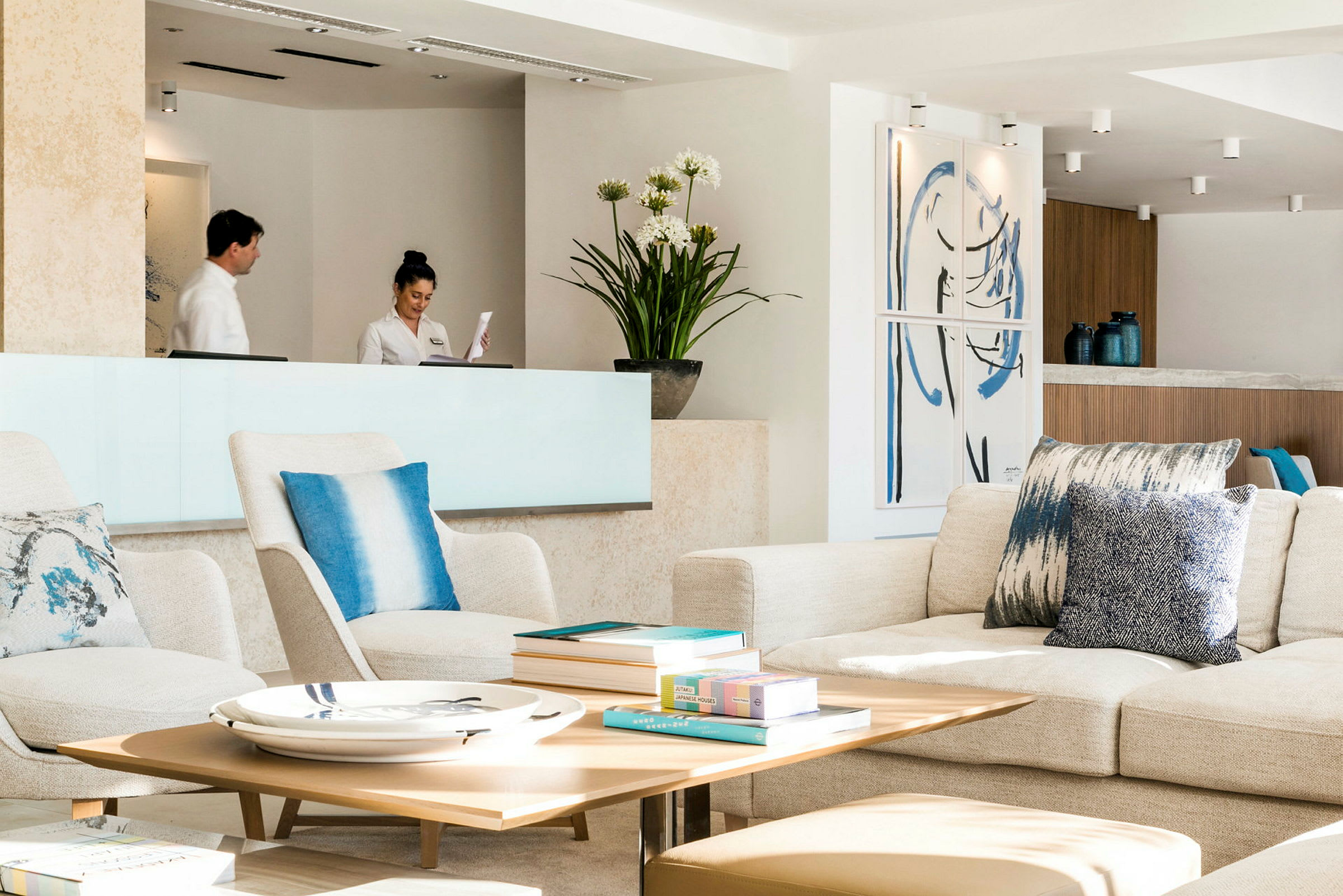 En lys og moderne hotellobby med siddepladser, et receptionsområde og dekorative genstande. (AI-genereret tekst)